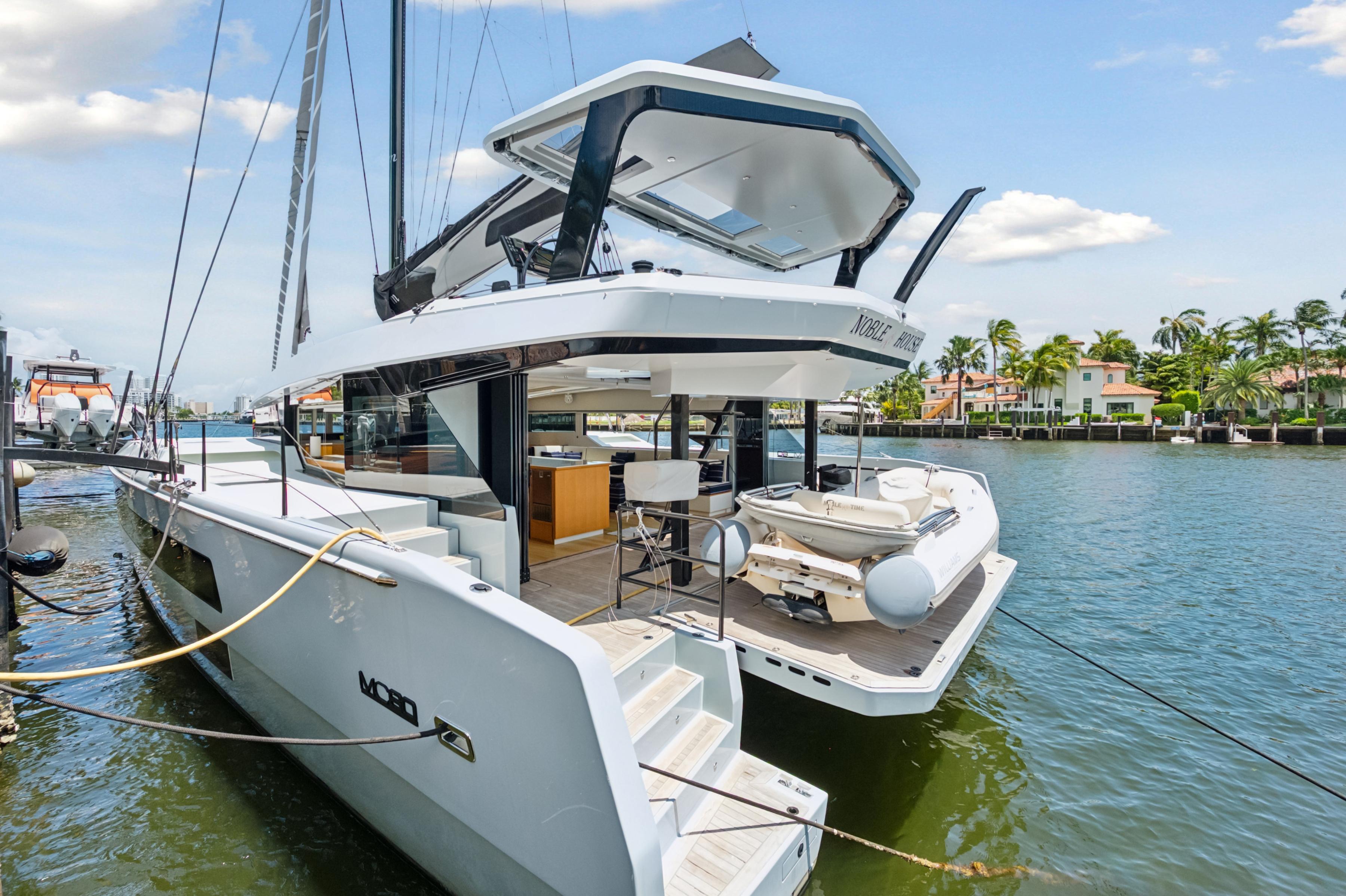2019 McConaghy MC60 yacht docked by waterfront homes, showcasing sleek design and luxury features.