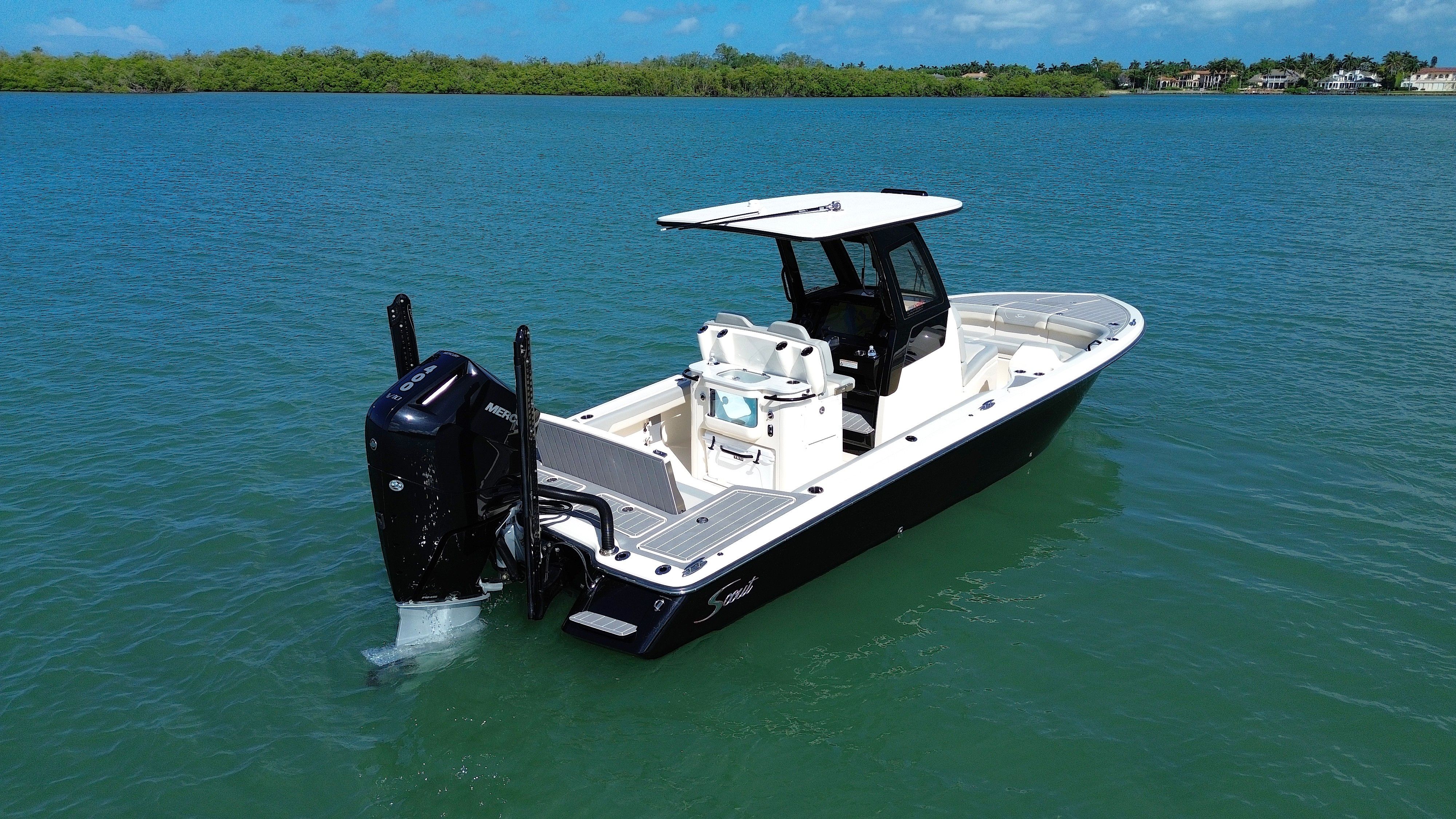 A 2024 Scout 281 XSS boat on calm water with an outboard motor and spacious deck.