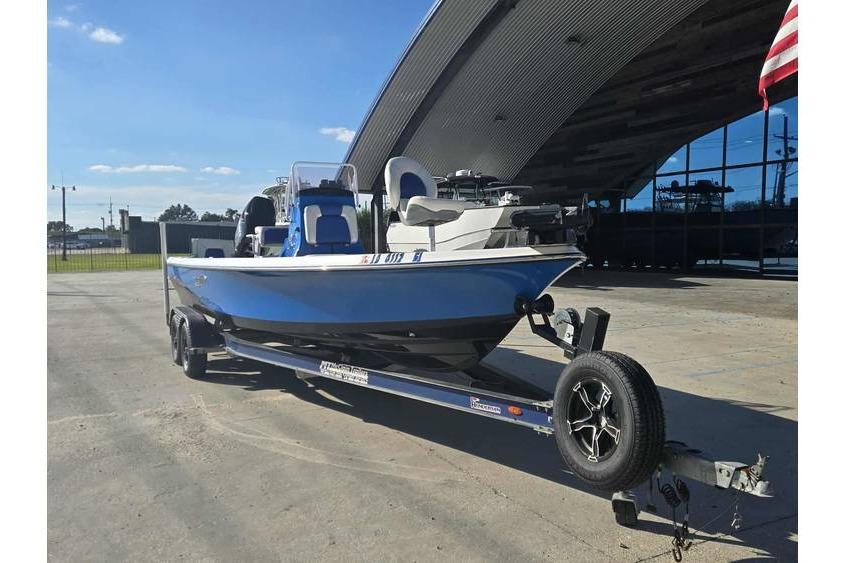 2020 Blue Wave 2400 PureBay boat on trailer, parked outdoors near a modern building.