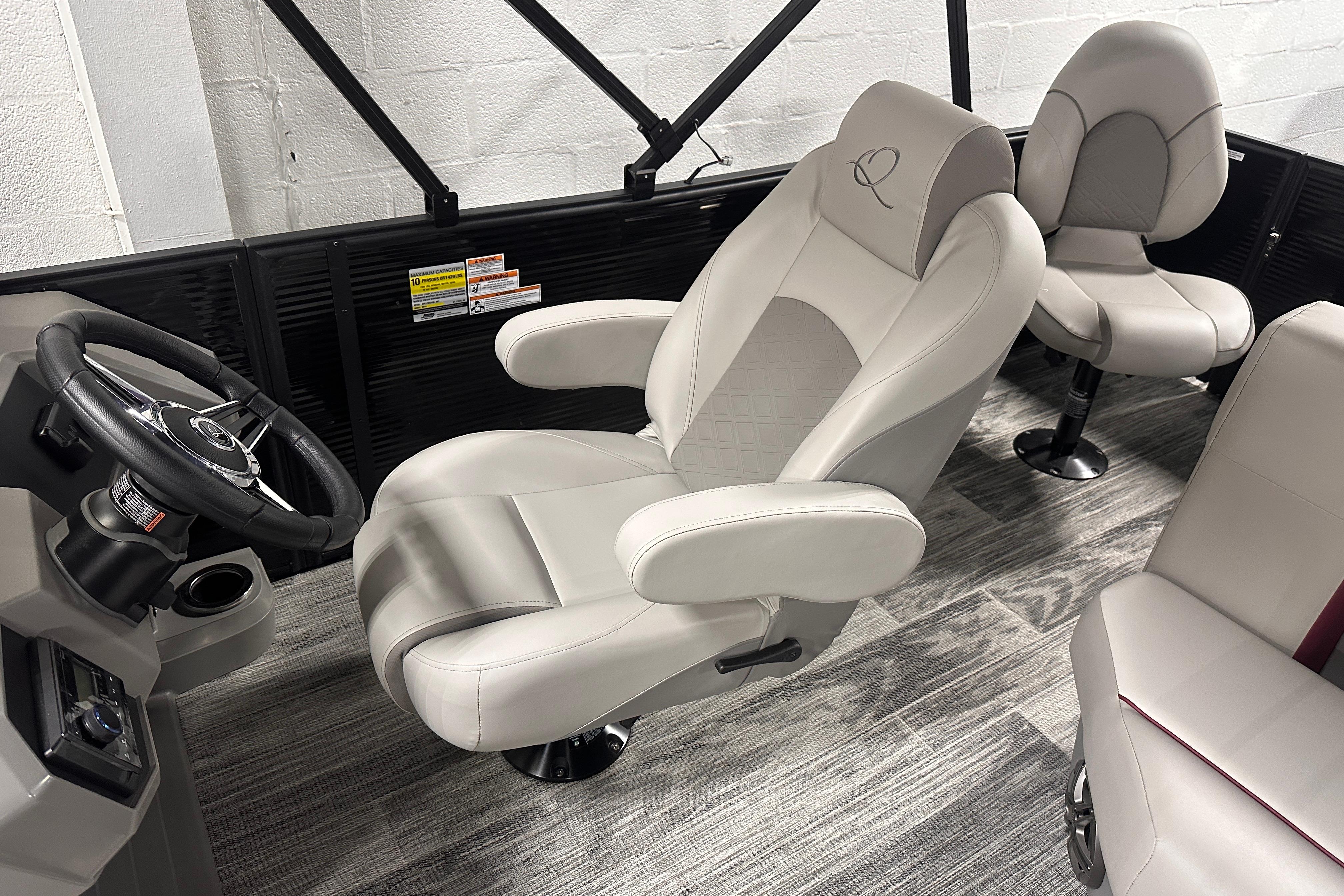 Luxurious interior of 2025 Qwest 18 XRE Cruise boat with plush seating and modern steering.