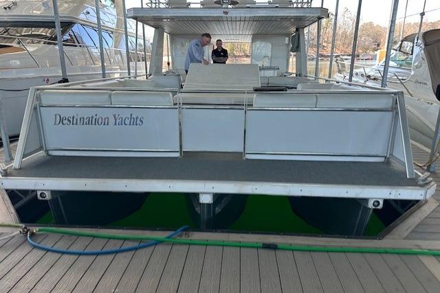 2008 Destination Yachts 45X14 houseboat docked, rear view with two people on deck.