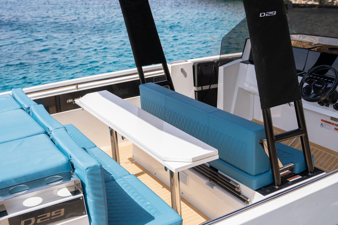 2026 De Antonio Yachts D29 interior with blue seating and sleek design on the water.
