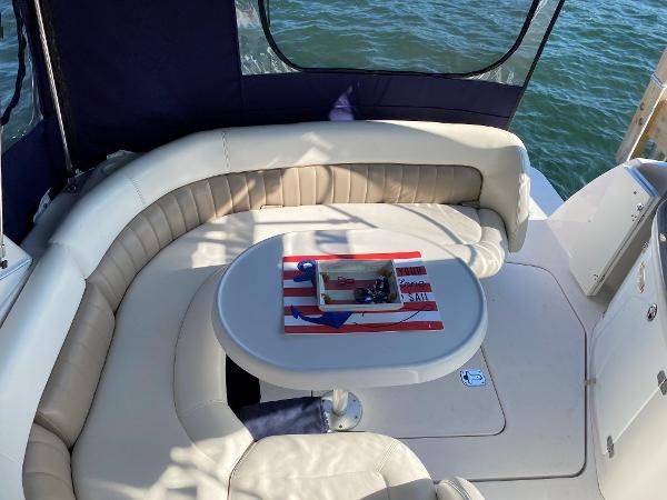 Interior of a boat with cream-colored seating and a table, surrounded by water.