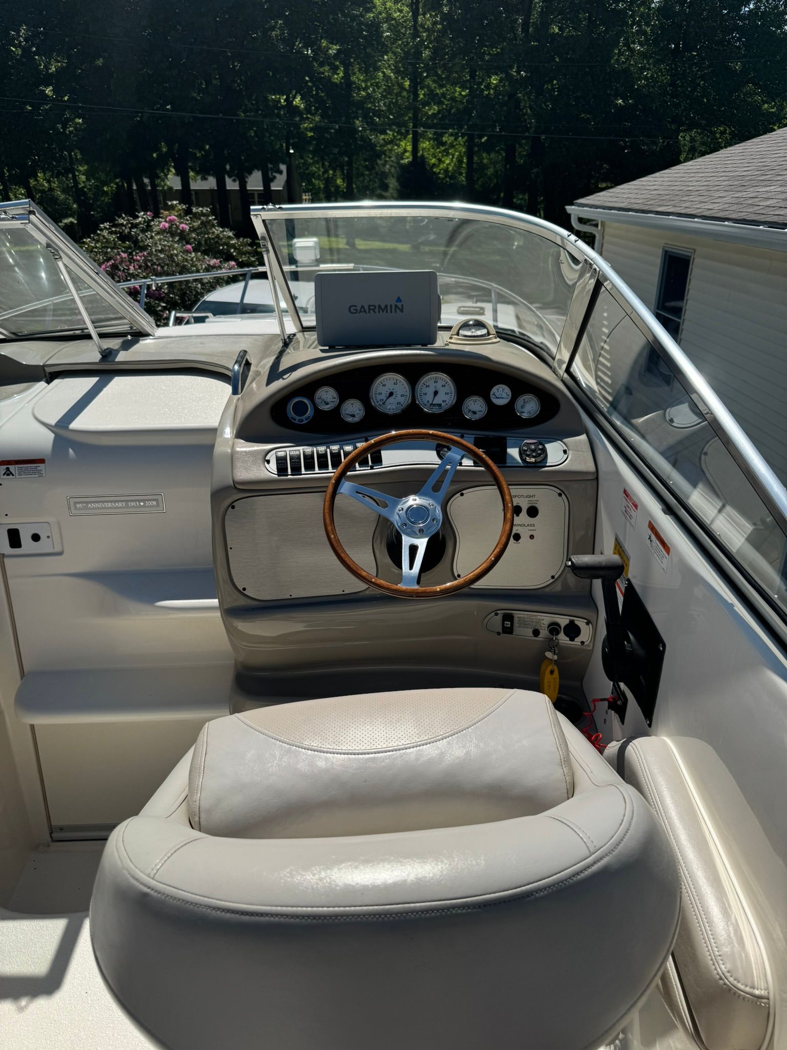The cockpit of a boat with a wooden steering wheel and multiple instruments.