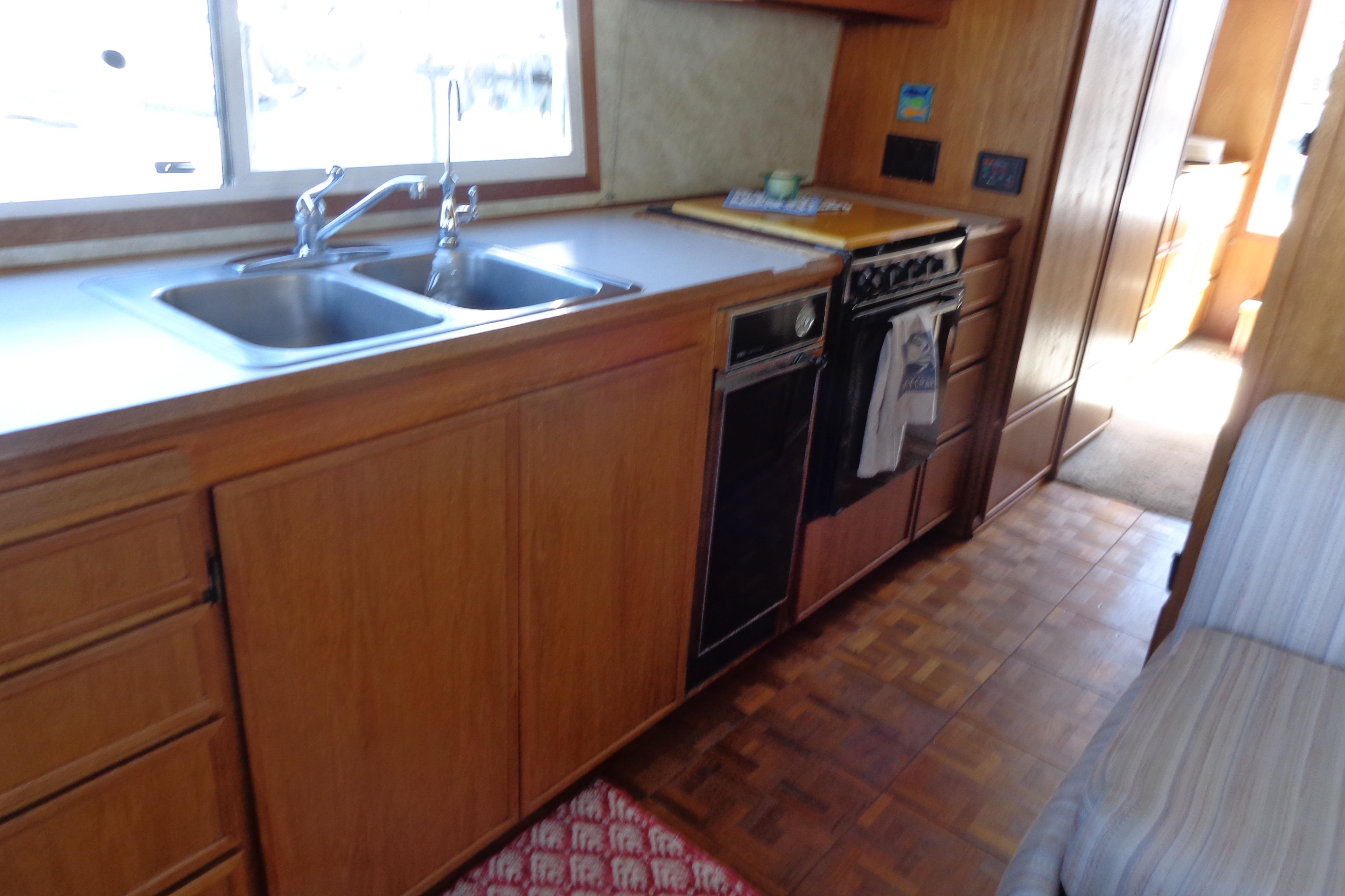 Interior of 1992 Cruise-A-Home Corsair 4200 kitchen with wooden cabinets and double sink.