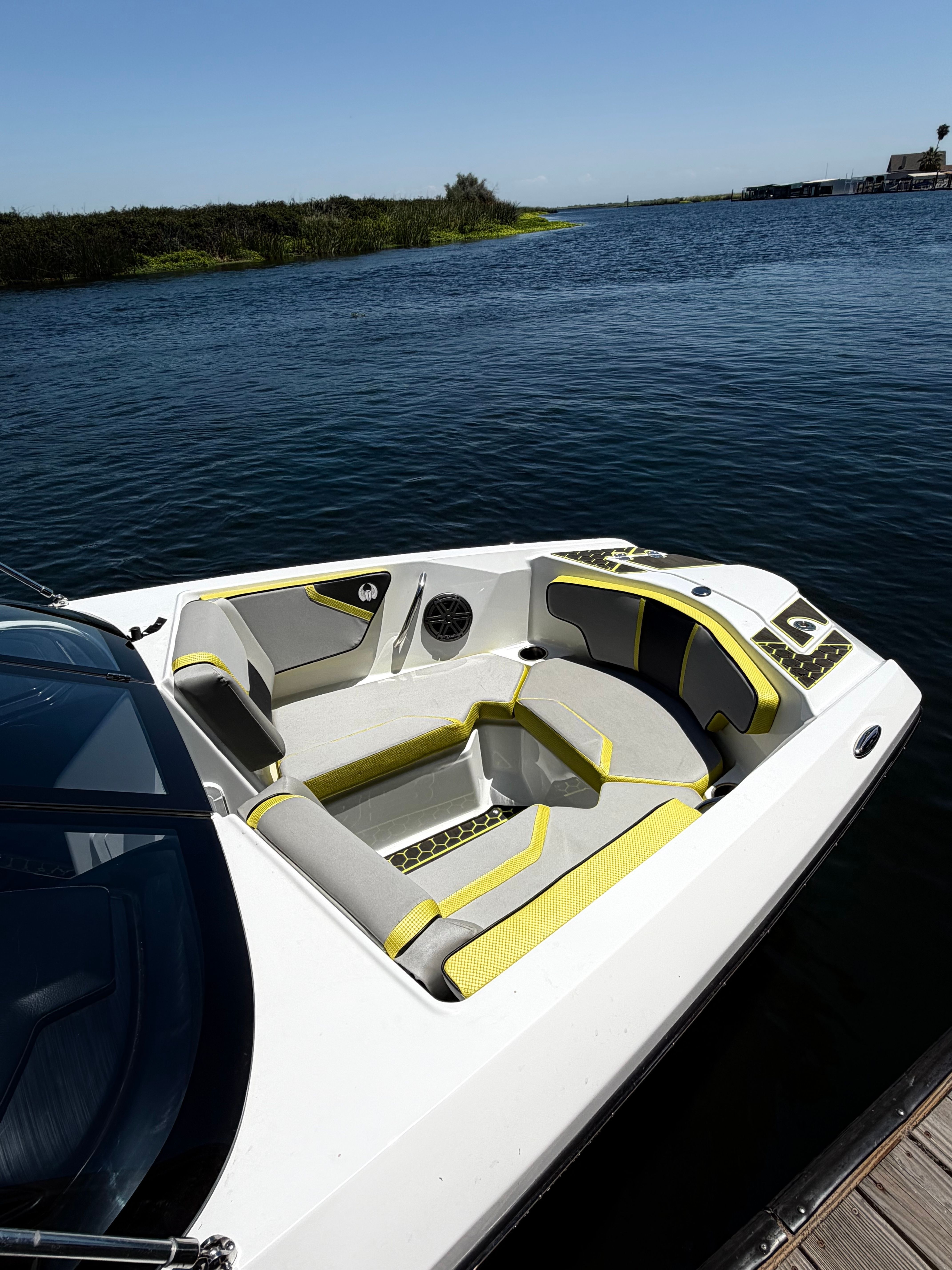 The image shows a modern 2023 Scarab 215 ID boat with stylish seating by the water.