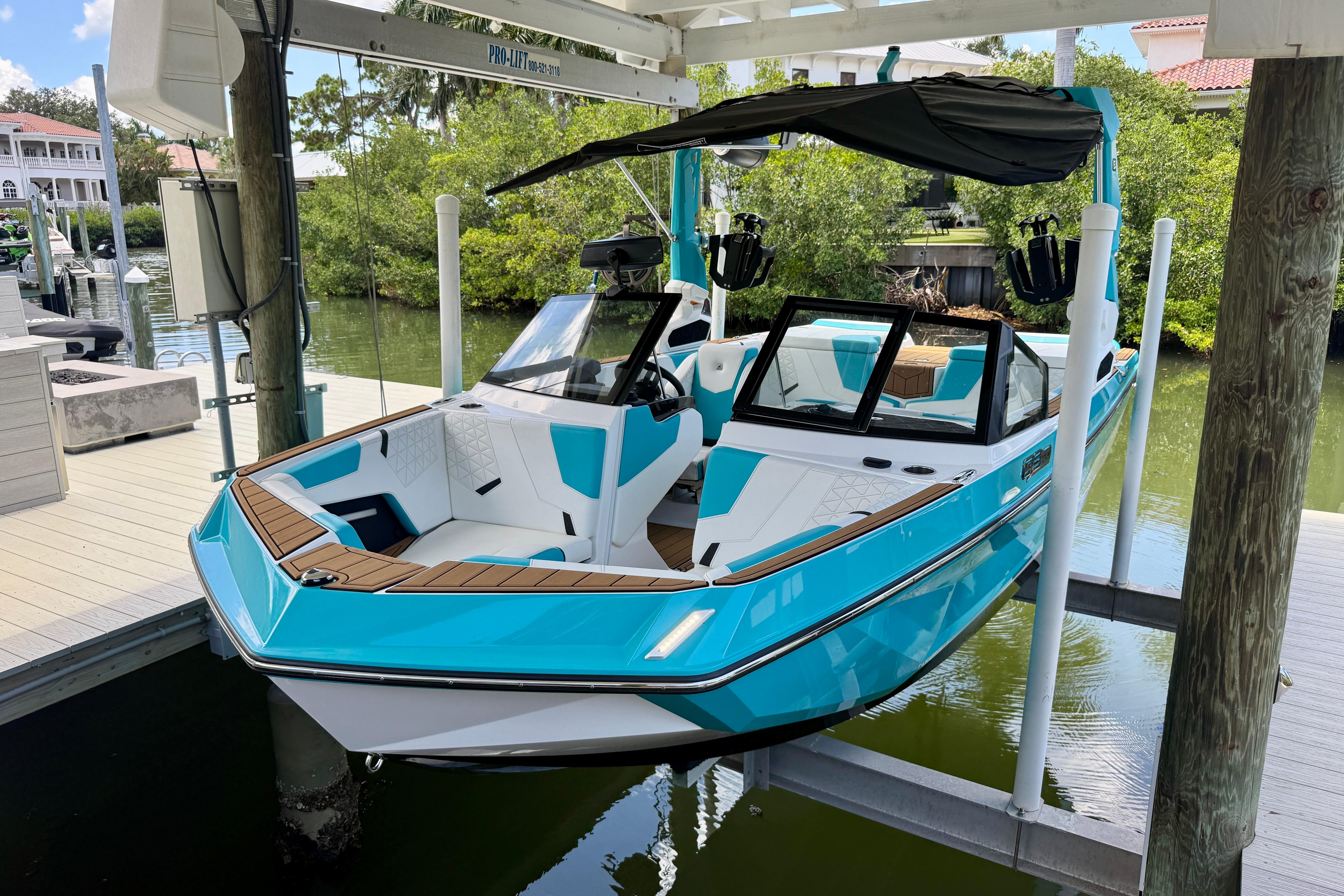 2024 Nautique Super Air Nautique GS20 boat in vibrant blue, docked on a lift.