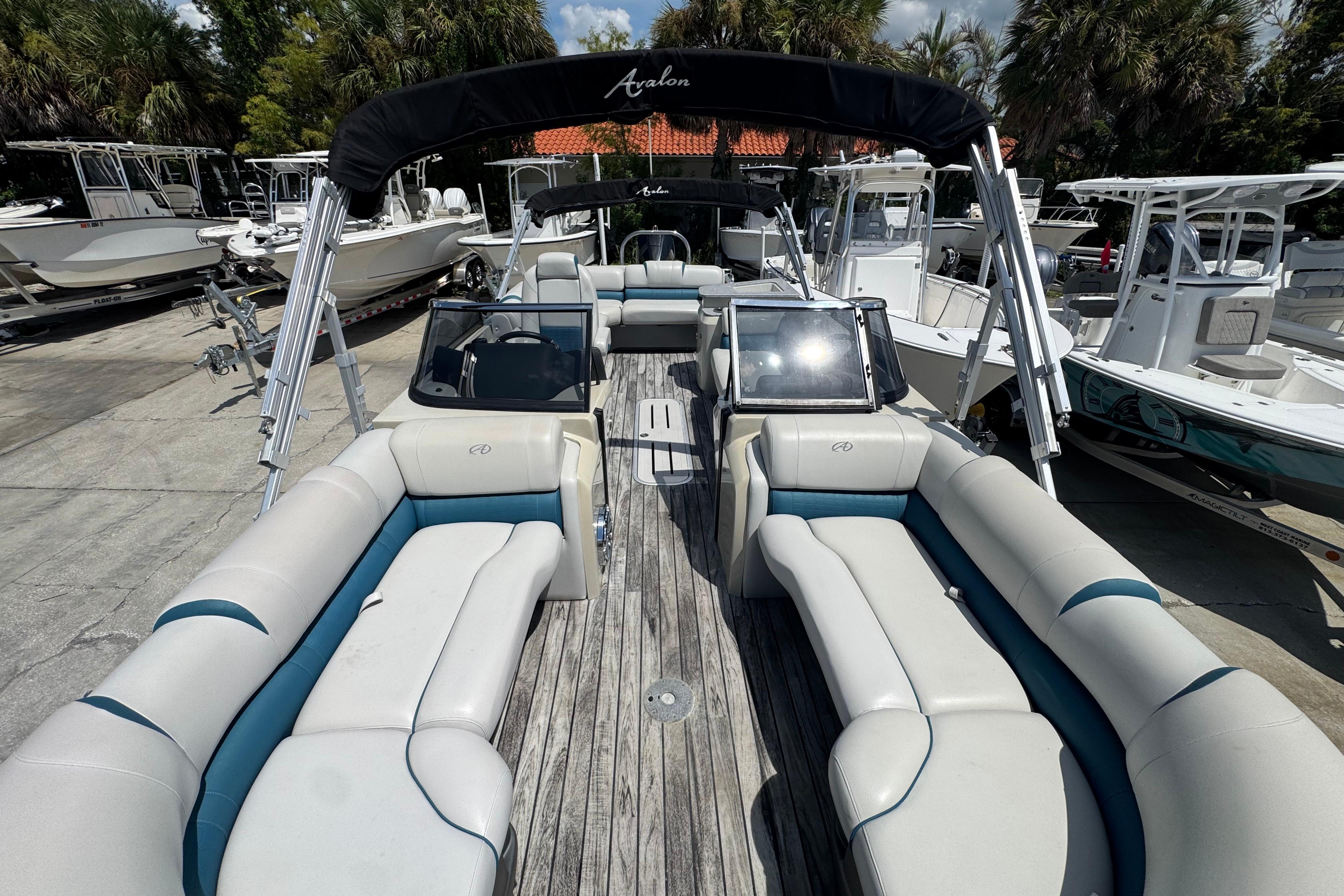 2019 Avalon Catalina Platinum Elite pontoon boat with spacious seating and windshield, docked among other boats.