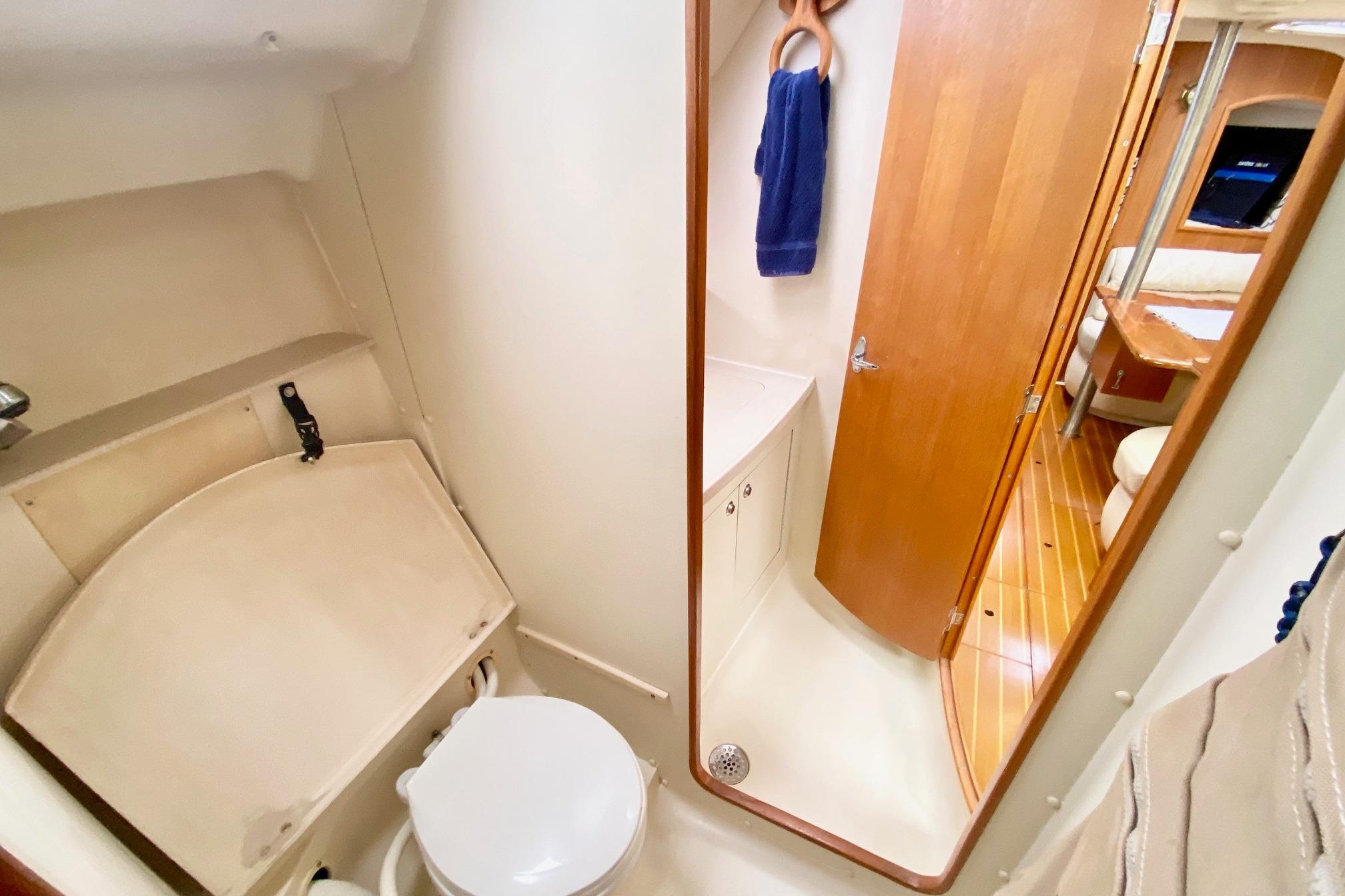 2003 Hunter 386 yacht bathroom with toilet, mirror, and wooden door.