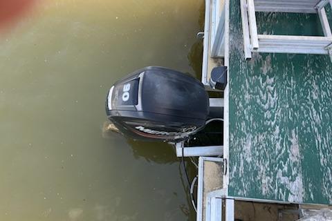 Outboard motor on a 1995 Myacht 40X13 houseboat docked on murky water.