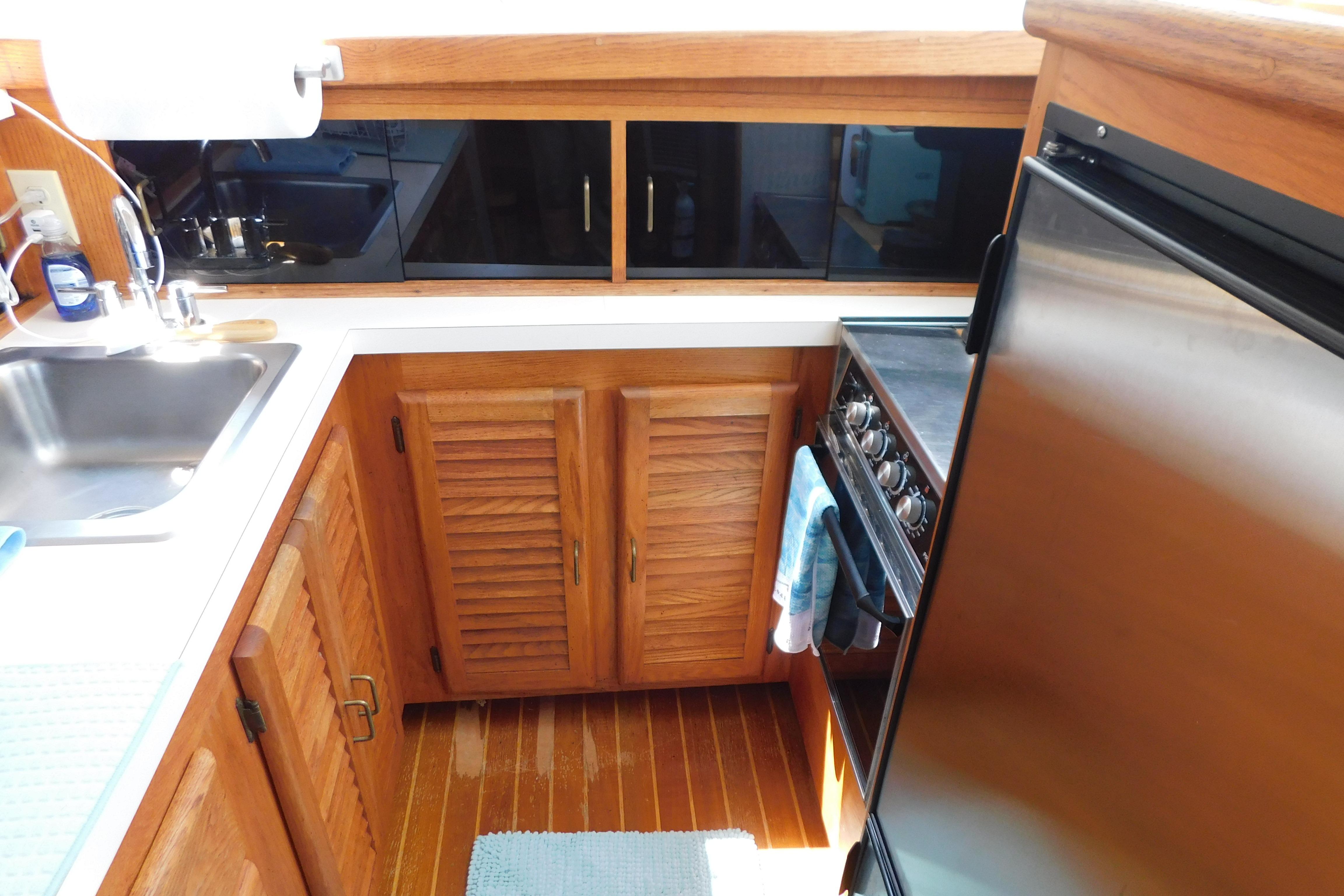 1987 Mainship 40 DC yacht kitchen with wooden cabinets, stainless steel appliances, and sink.