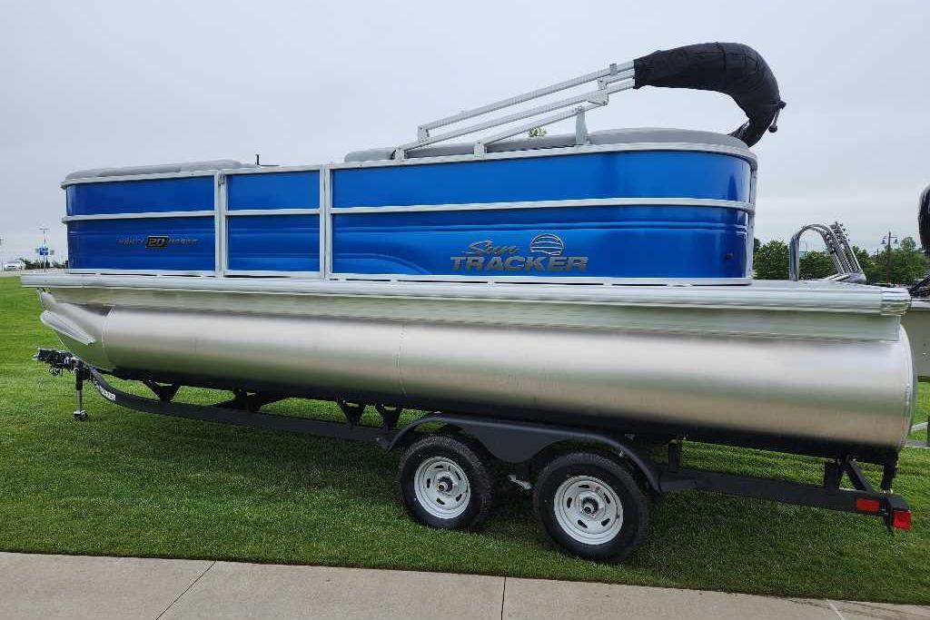 2026 Sun Tracker Party Barge 20 DLX pontoon boat on trailer, parked on grass.