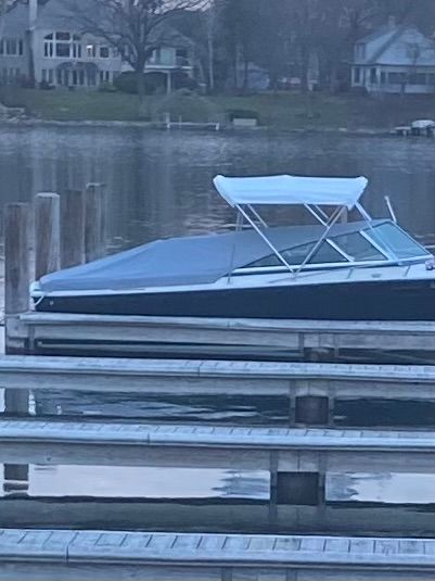 A blue boat with a white canopy is docked at a calm pier.