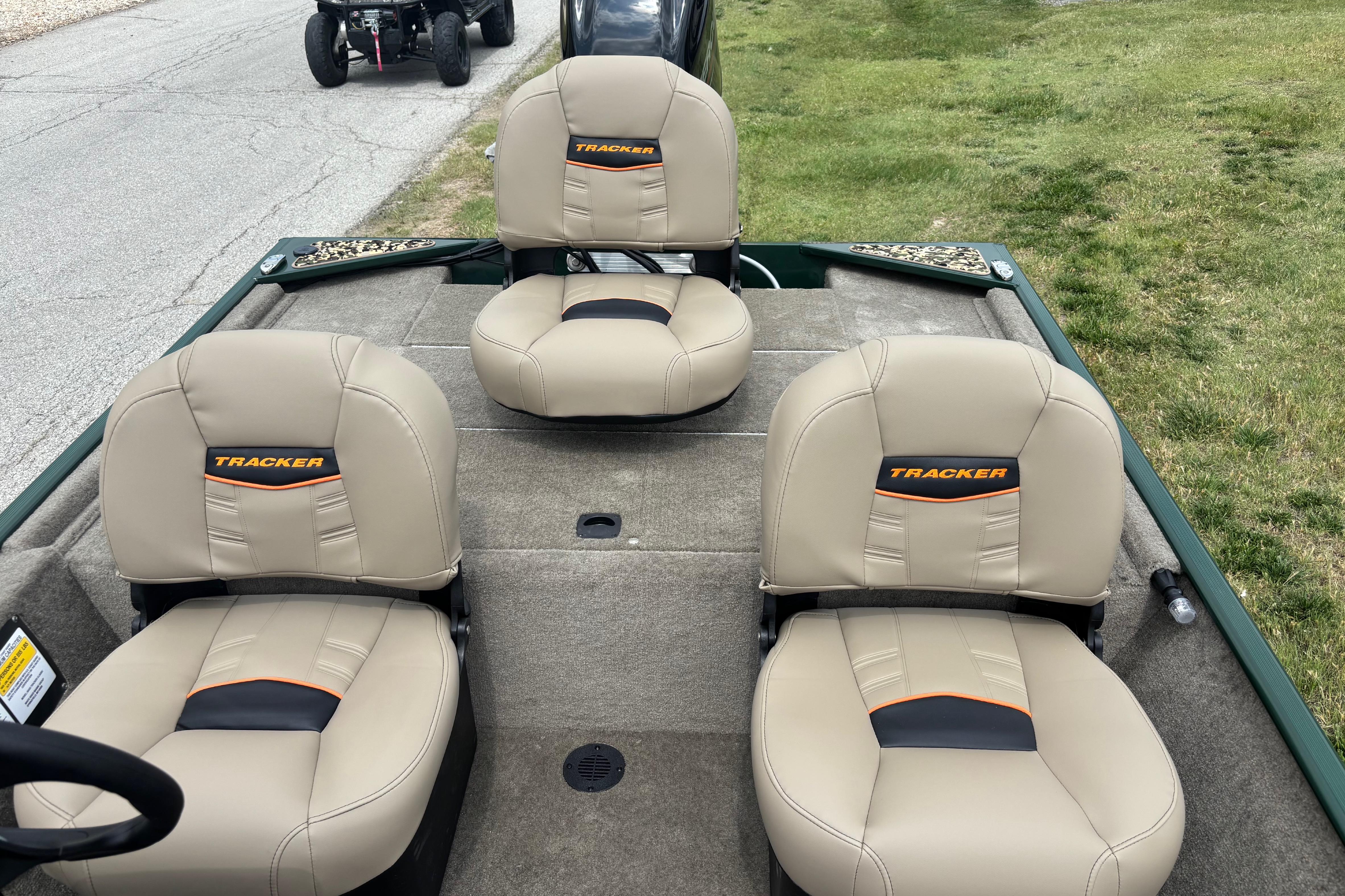 2026 Tracker Bass Tracker Classic Limited boat seats, beige with orange accents, on grassy area.