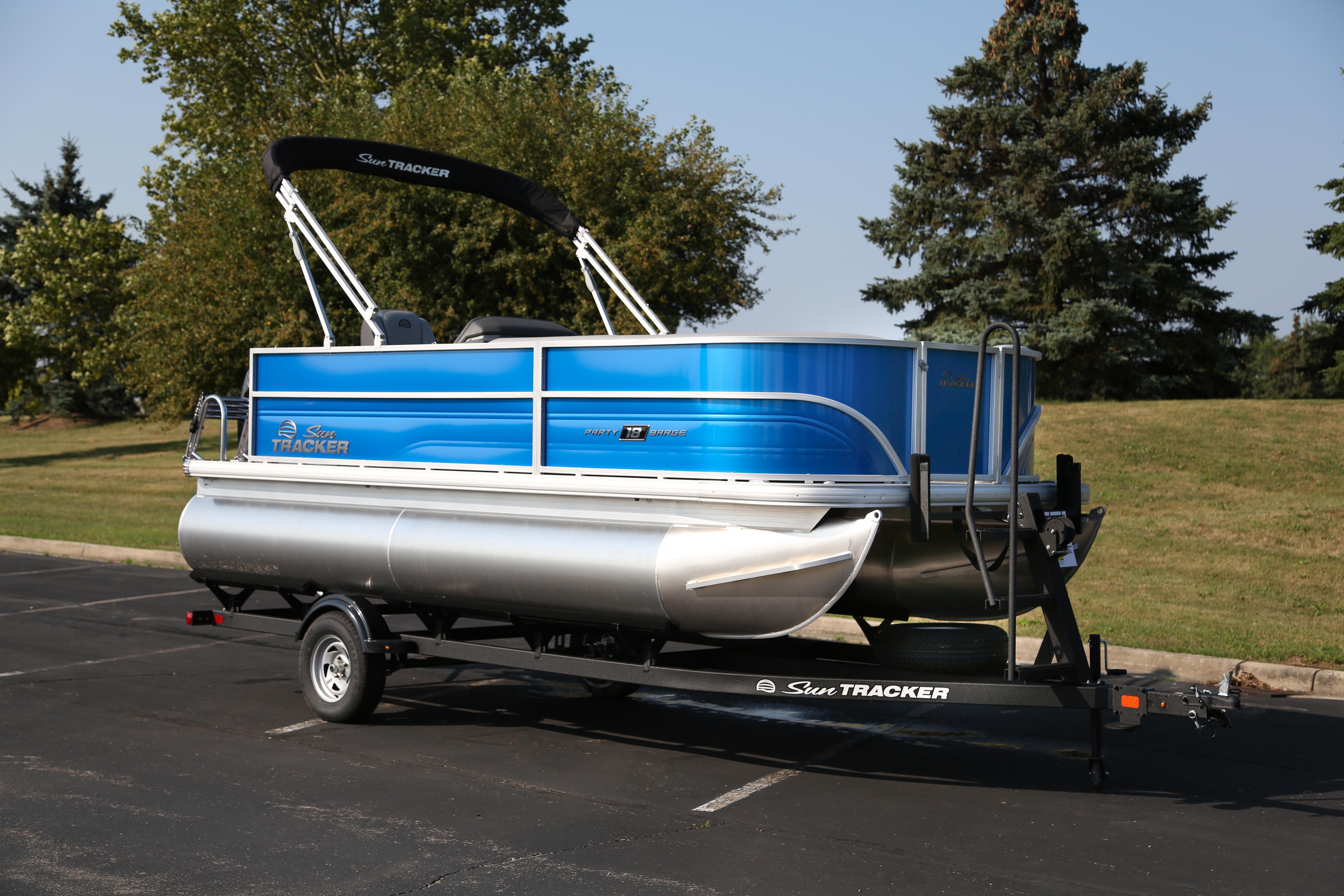 2026 Sun Tracker Party Barge 18 DLX pontoon boat on trailer in parking lot.