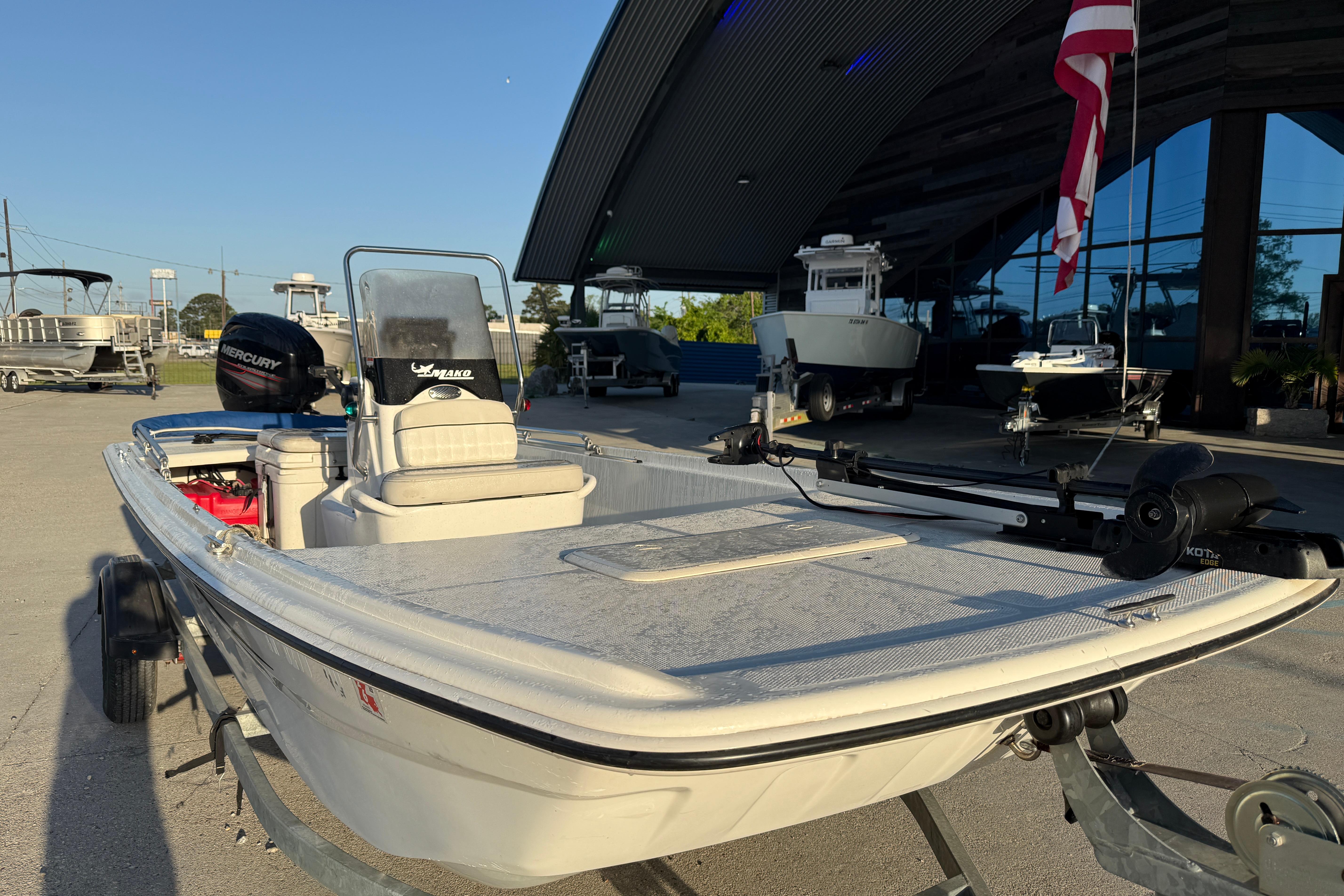 2017 Mako Pro Skiff 17 CC boat on trailer, parked outside dealership.