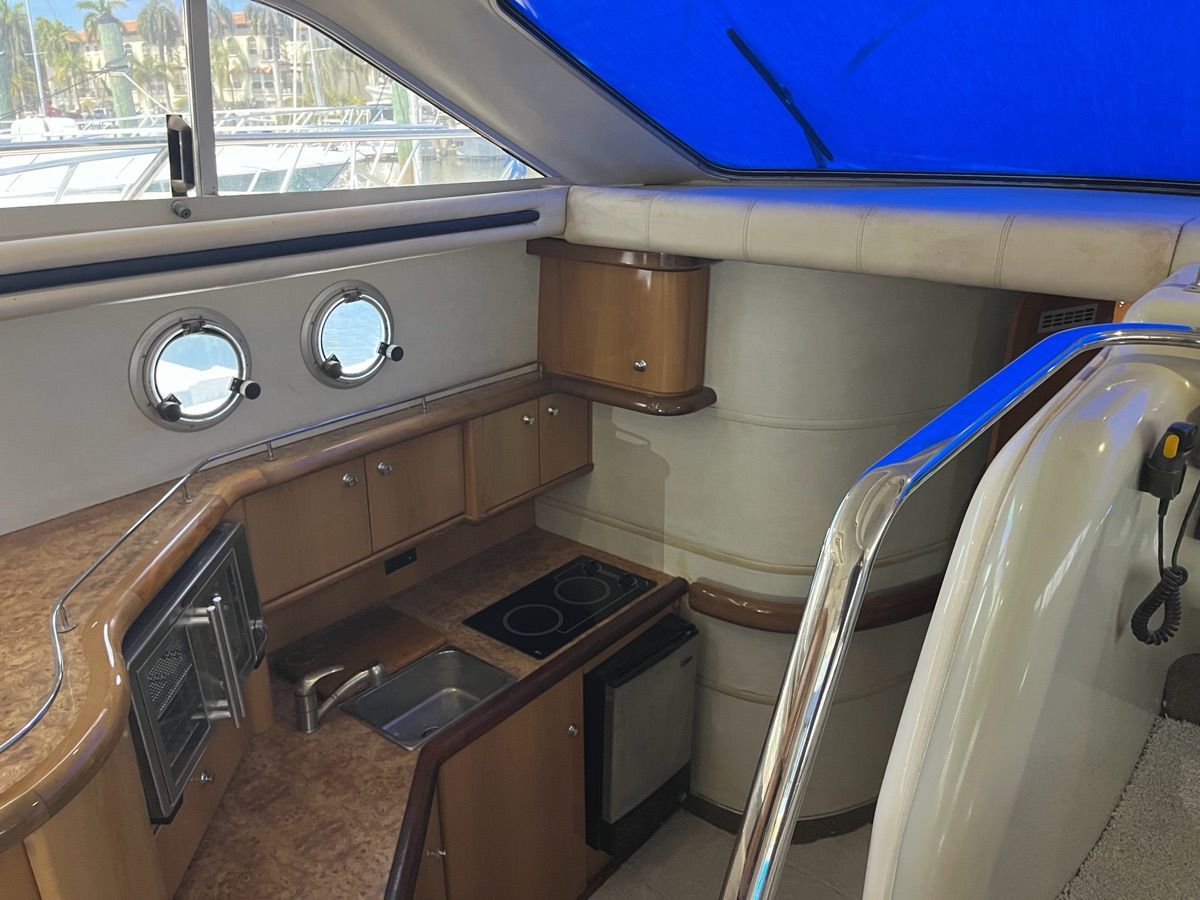 The galley of a 1999 Sealine F44 with wooden cabinets and a blue cover.