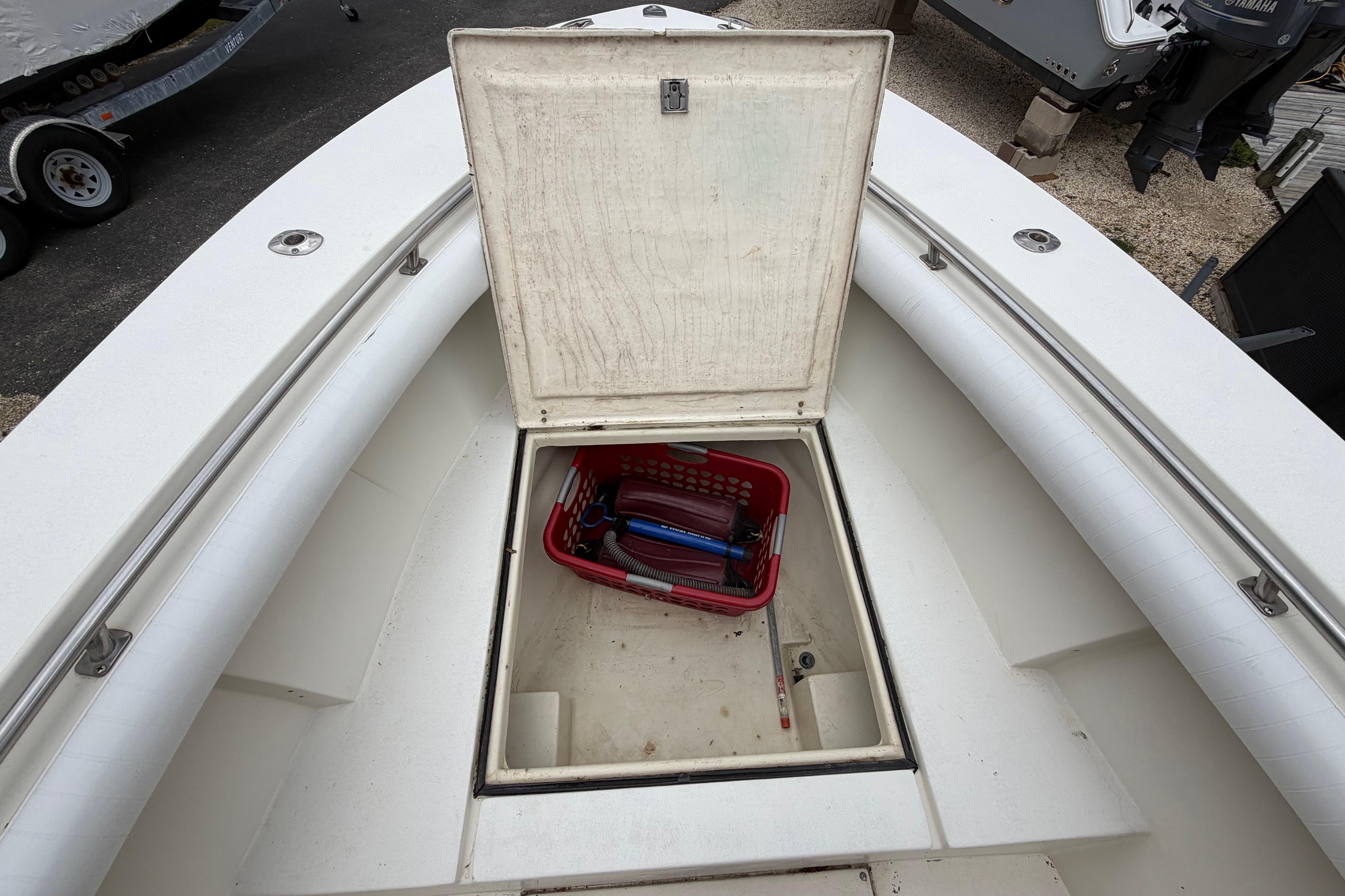 Open storage compartment on 1985 SeaCraft SC 23 Classic boat with tools inside.