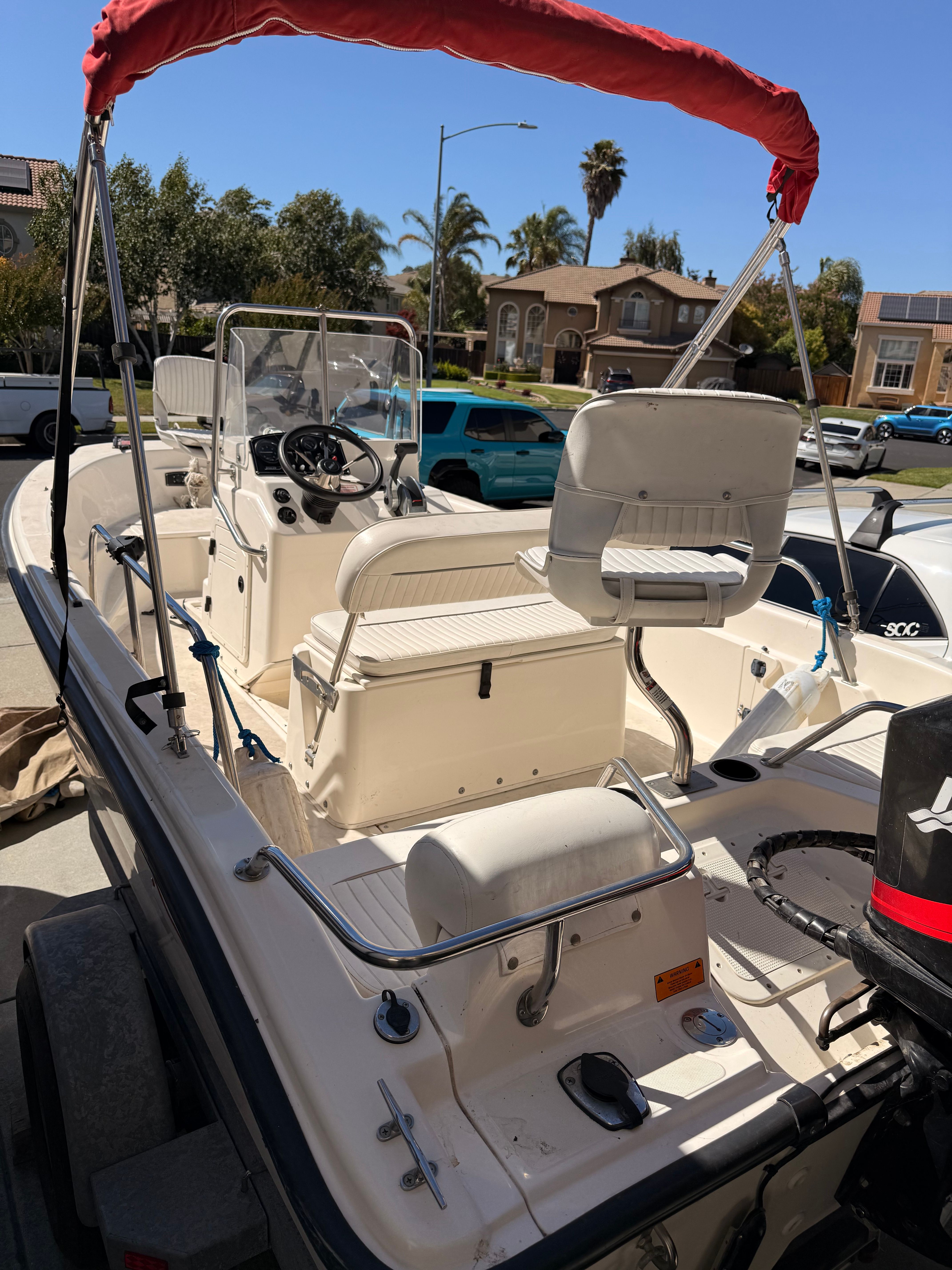A 2002 Boston Whaler 160 Dauntless with a red sunshade and steering console.