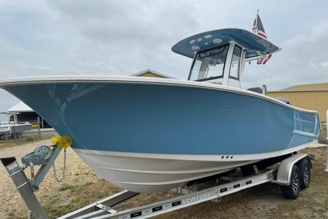 2026 Sportsman Heritage 231 Center Console boat on trailer, blue hull, American flag displayed.