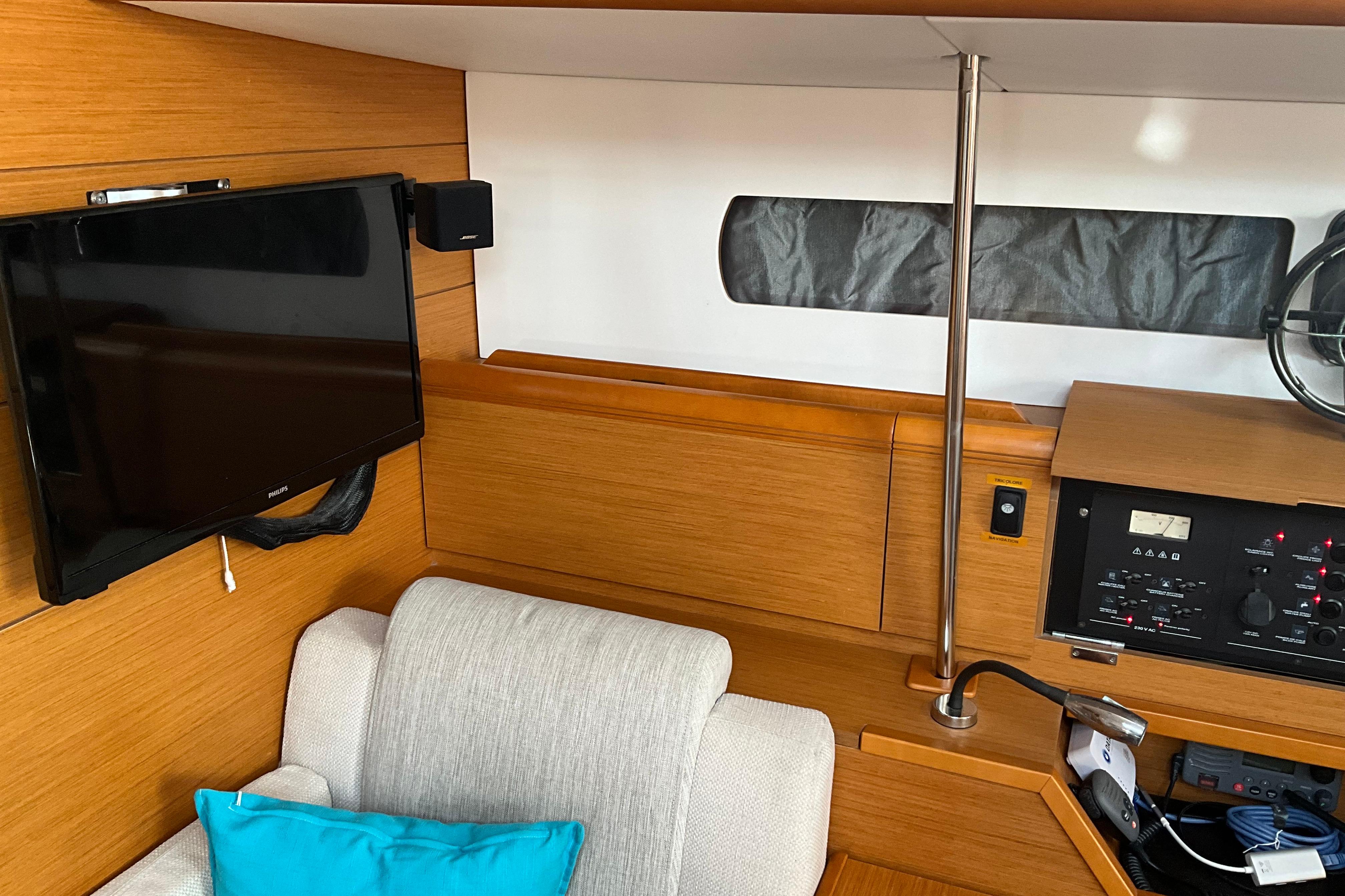 Interior of 2015 Jeanneau Sun Odyssey 469 yacht with TV, control panel, and seating area.