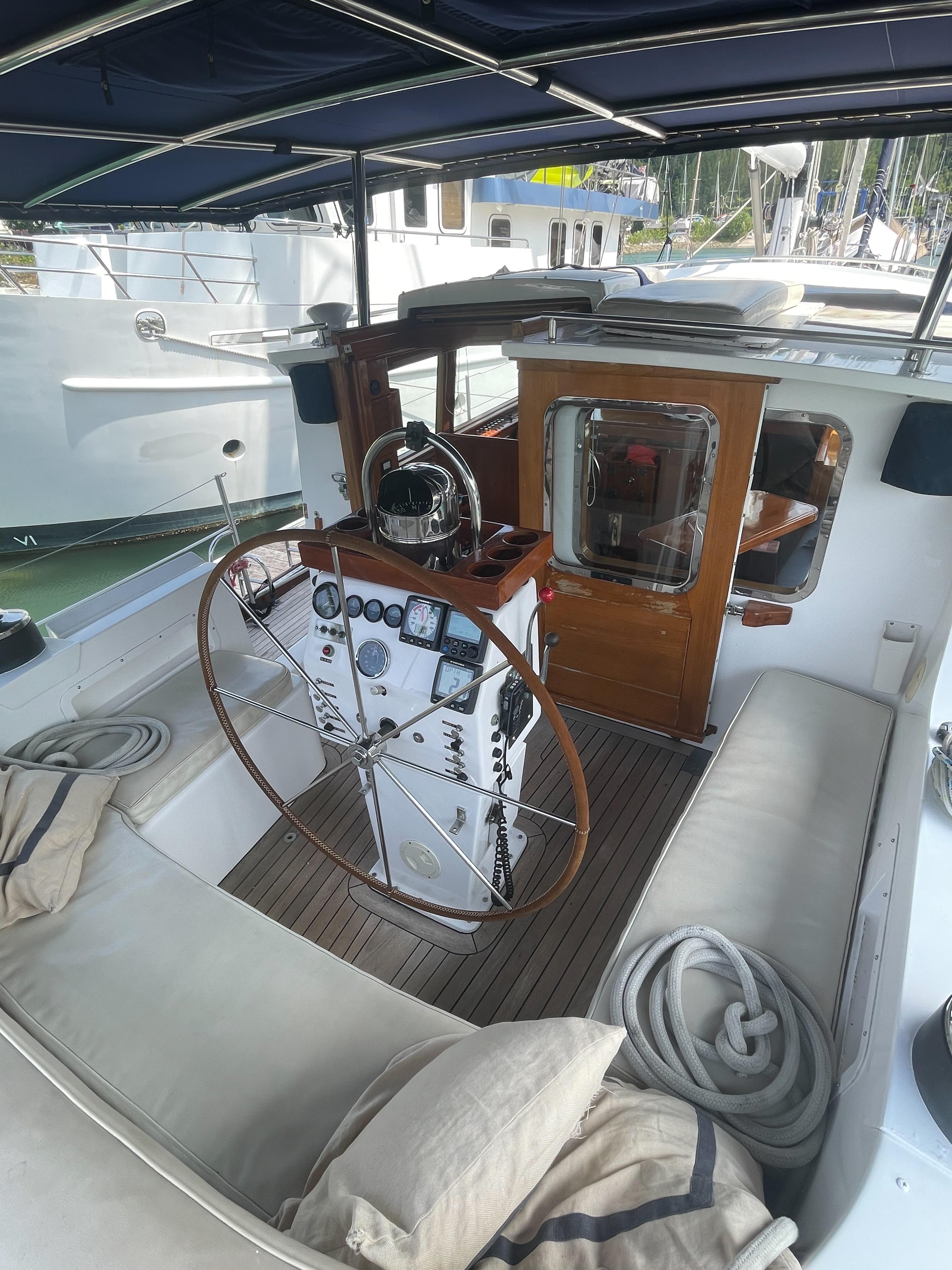 1988 Cooper 60 yacht cockpit with wooden helm, cushioned seating, and nautical equipment.
