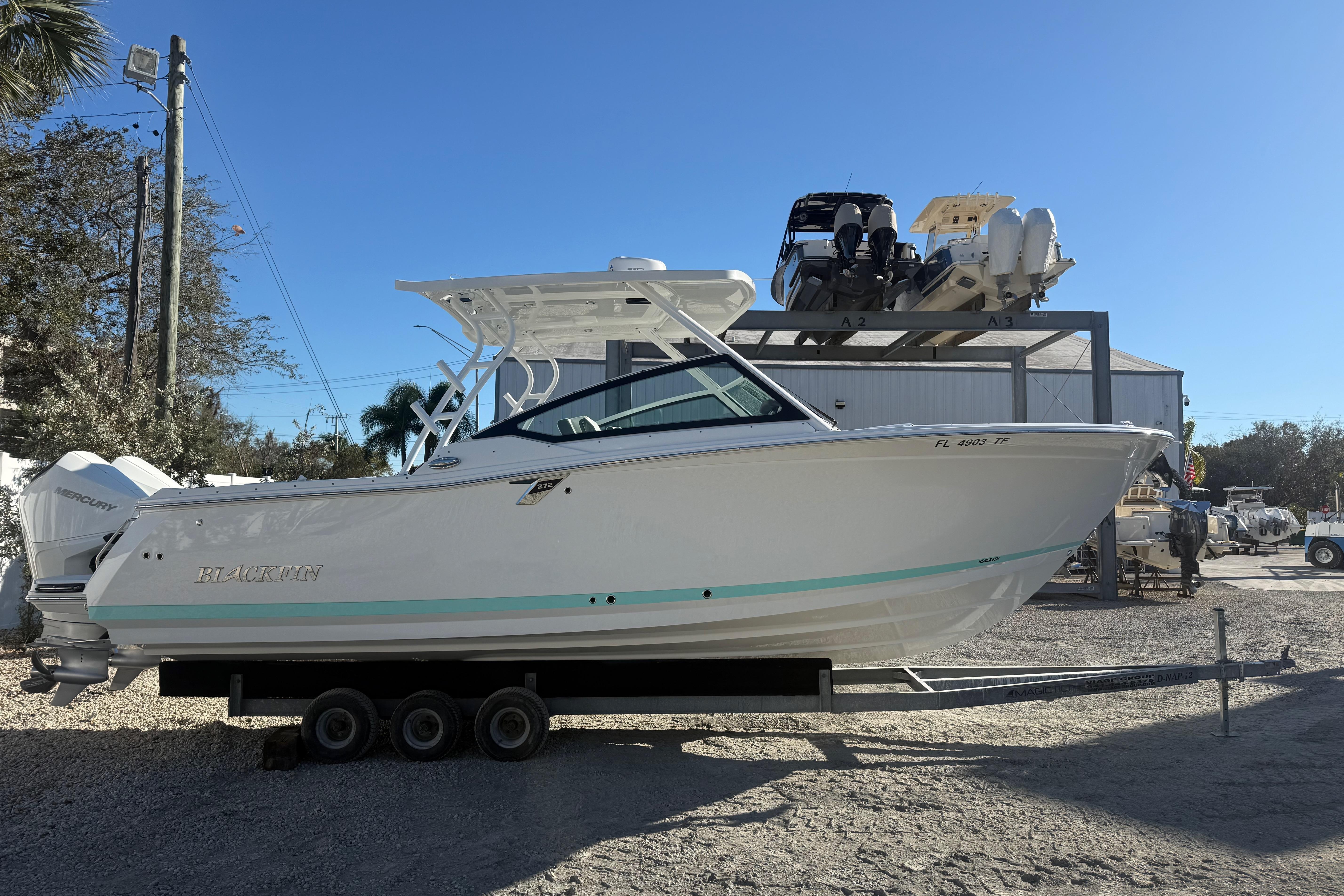 2022 Blackfin 272 DC boat on trailer, outdoor storage, clear blue sky.