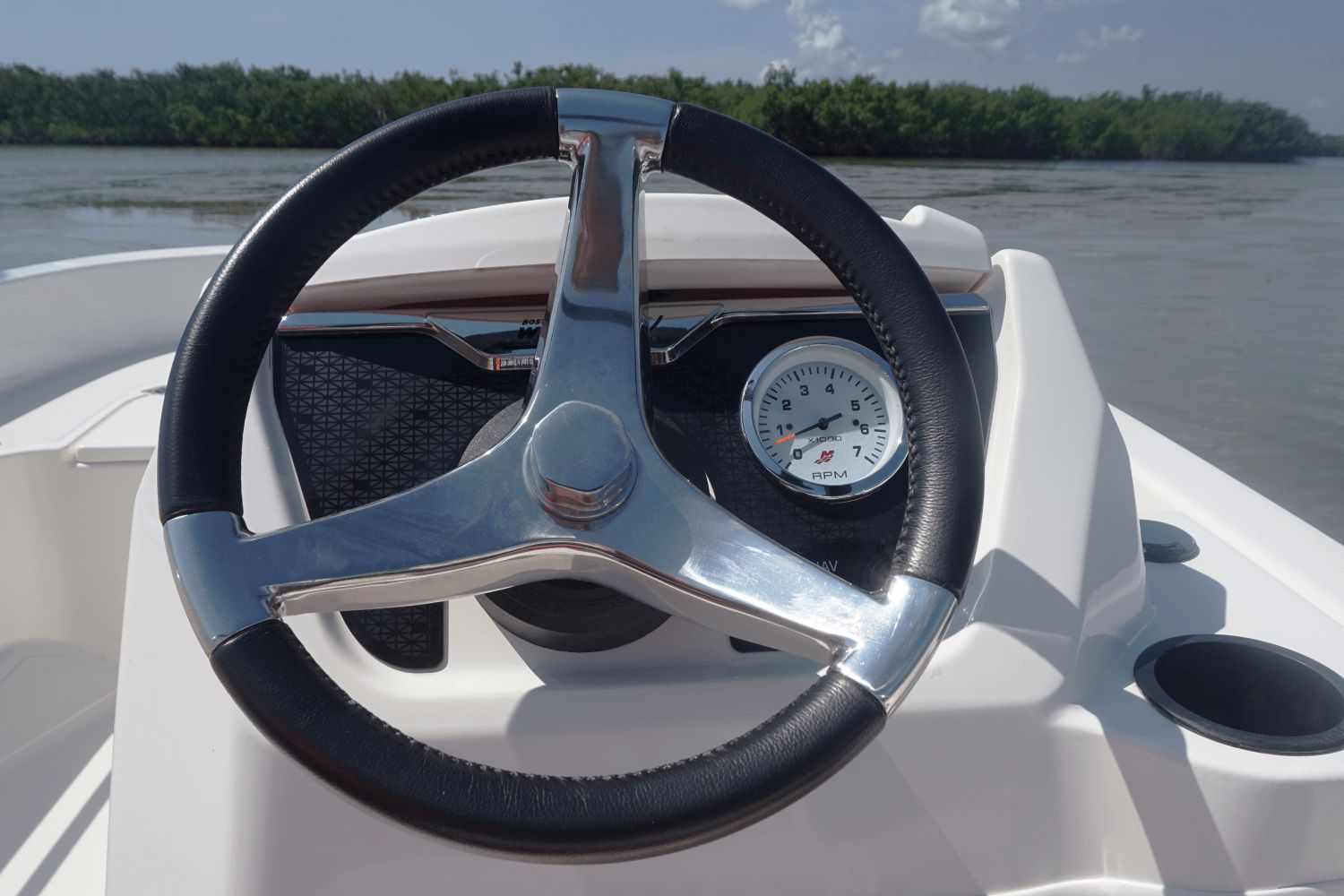The image shows the helm of a 2026 Boston Whaler 130 Super Sport on calm water.