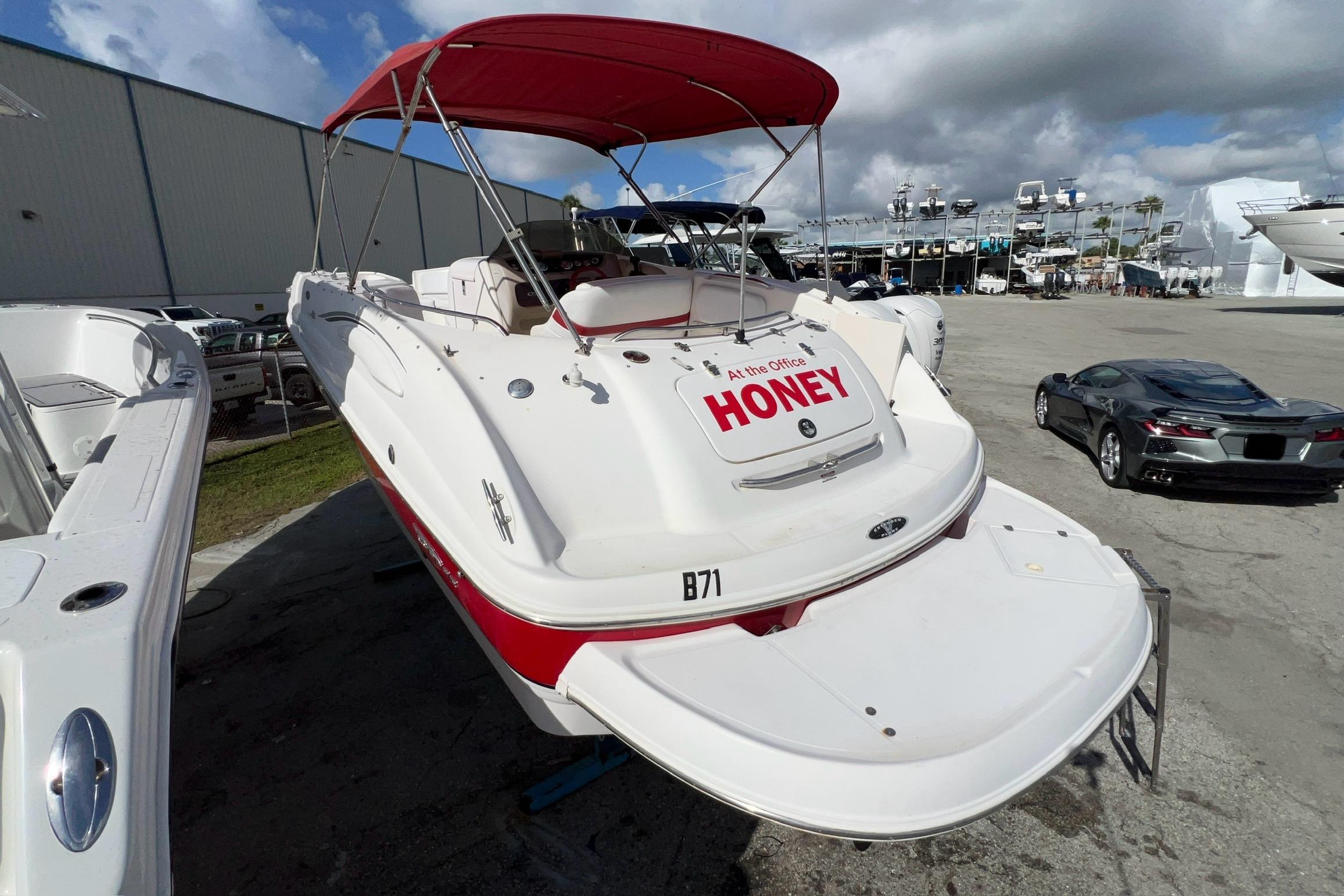 2002 Chaparral 232 Sunesta boat with red canopy, docked outdoors under cloudy sky.
