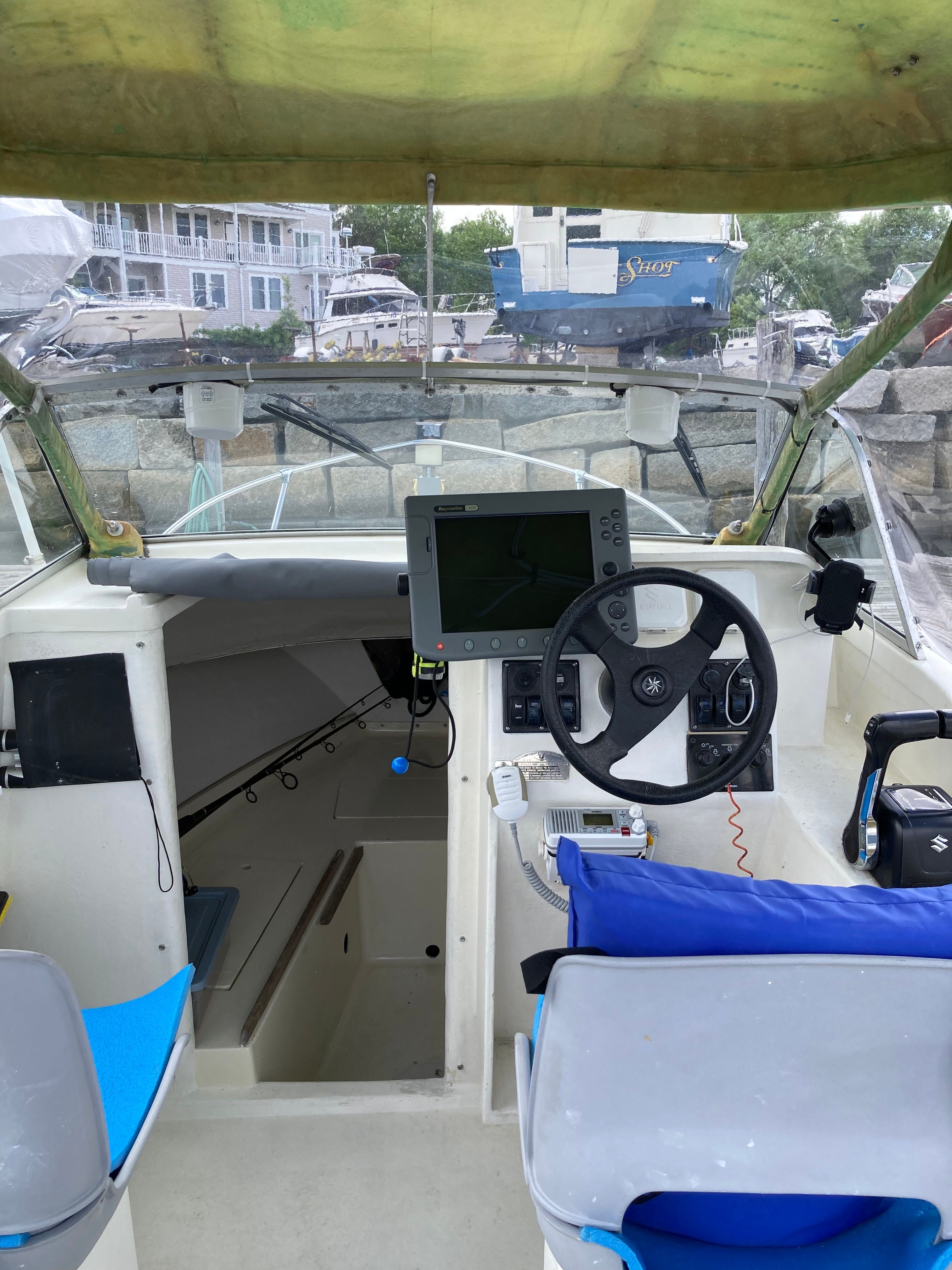 The cockpit of a 1969 Bertram Bahia Mar with steering wheel, electronics, and blue seats.
