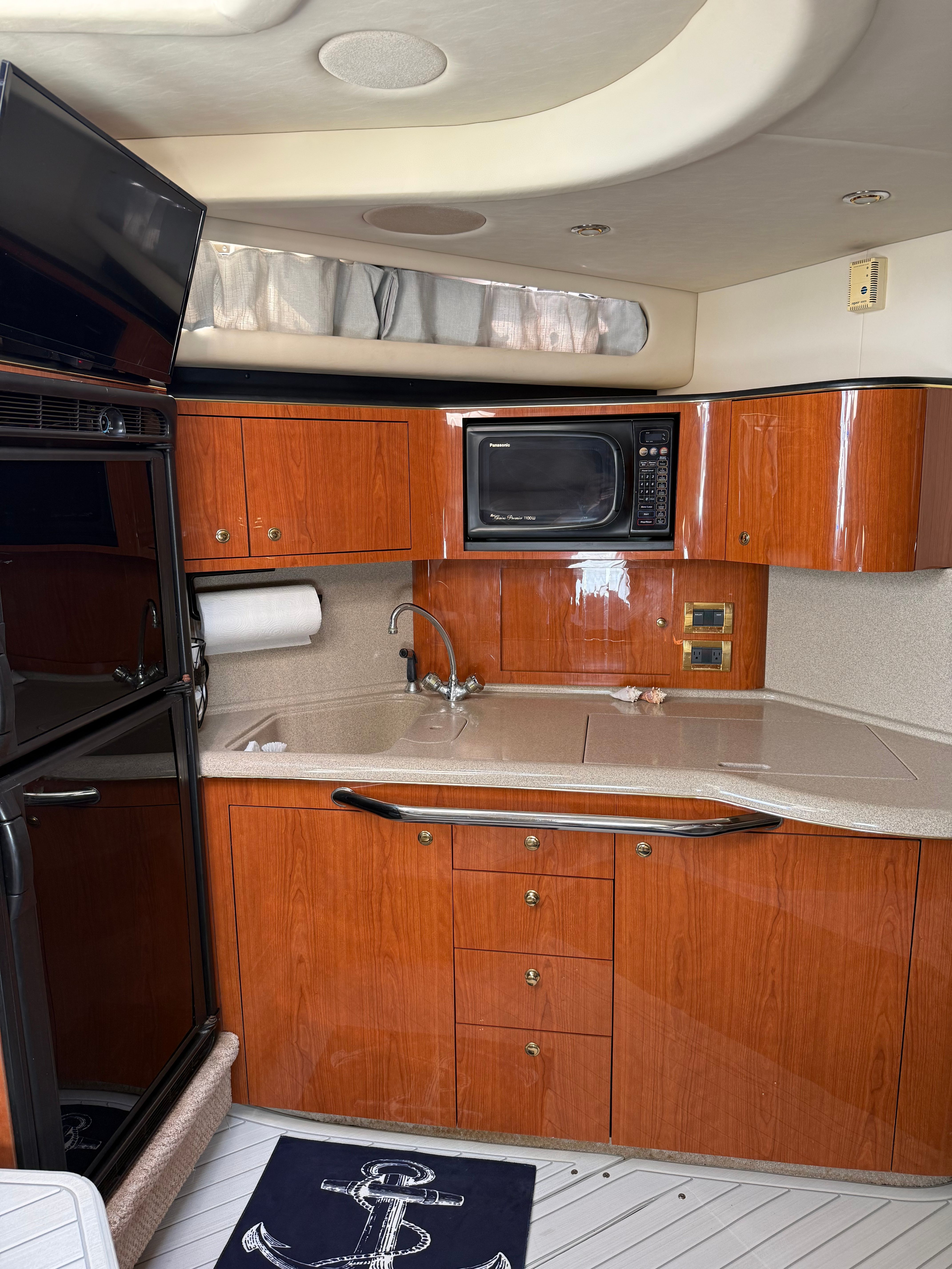 Interior of a Sea Ray 380 Sundancer with wooden cabinetry and kitchen appliances.