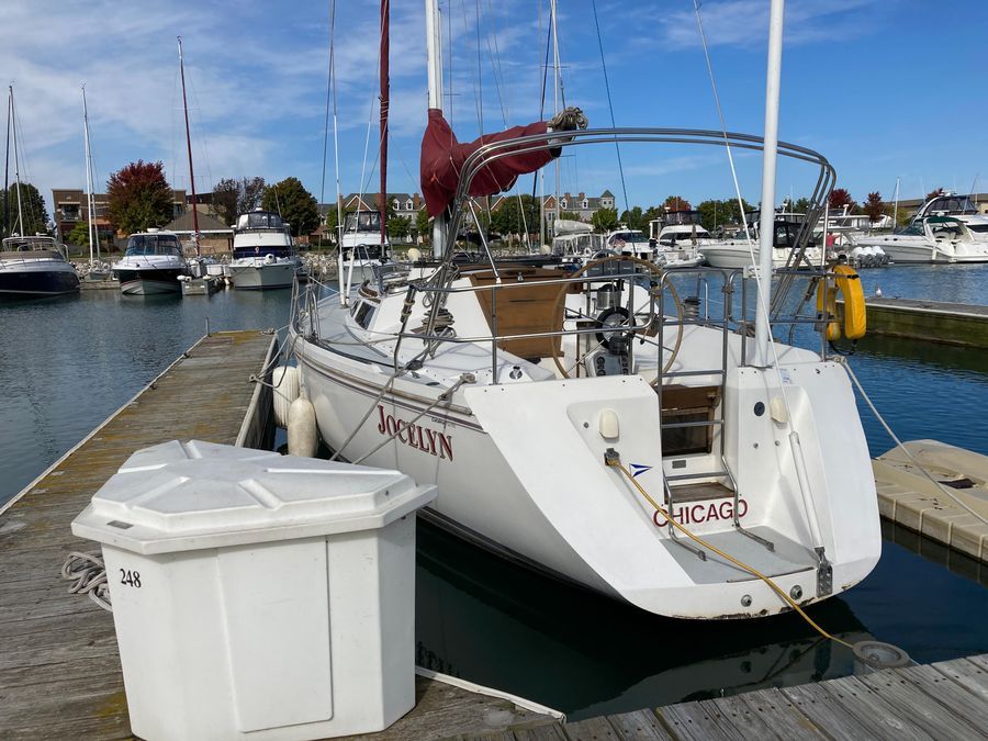 A 1990 Catalina 42 Tricabin docked at a marina, surrounded by other boats.