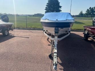 2005 Bayliner 205 Bowrider boat on trailer, covered, parked outdoors.