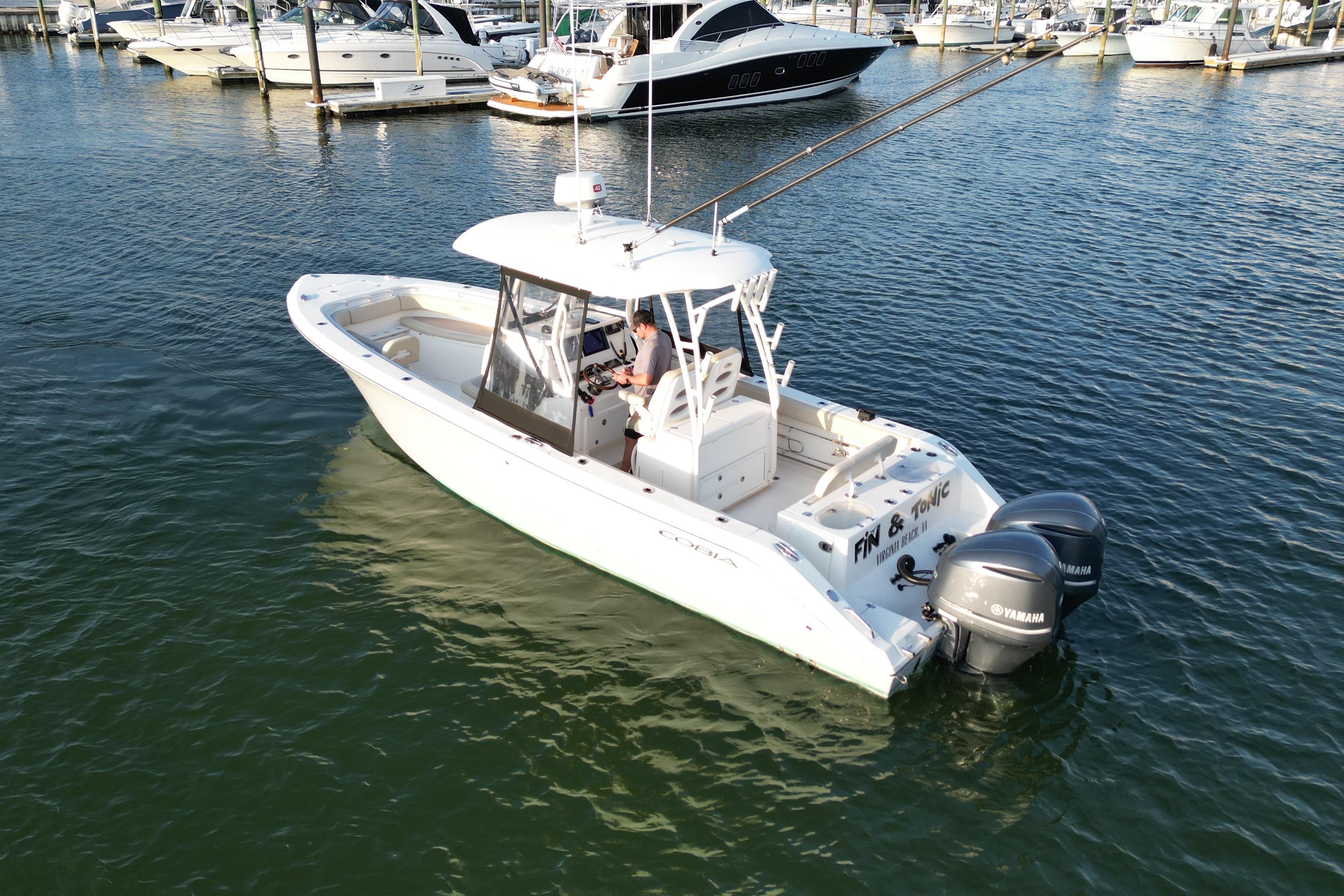 2016 Cobia 296 Center Console boat with dual Yamaha engines in a marina setting.