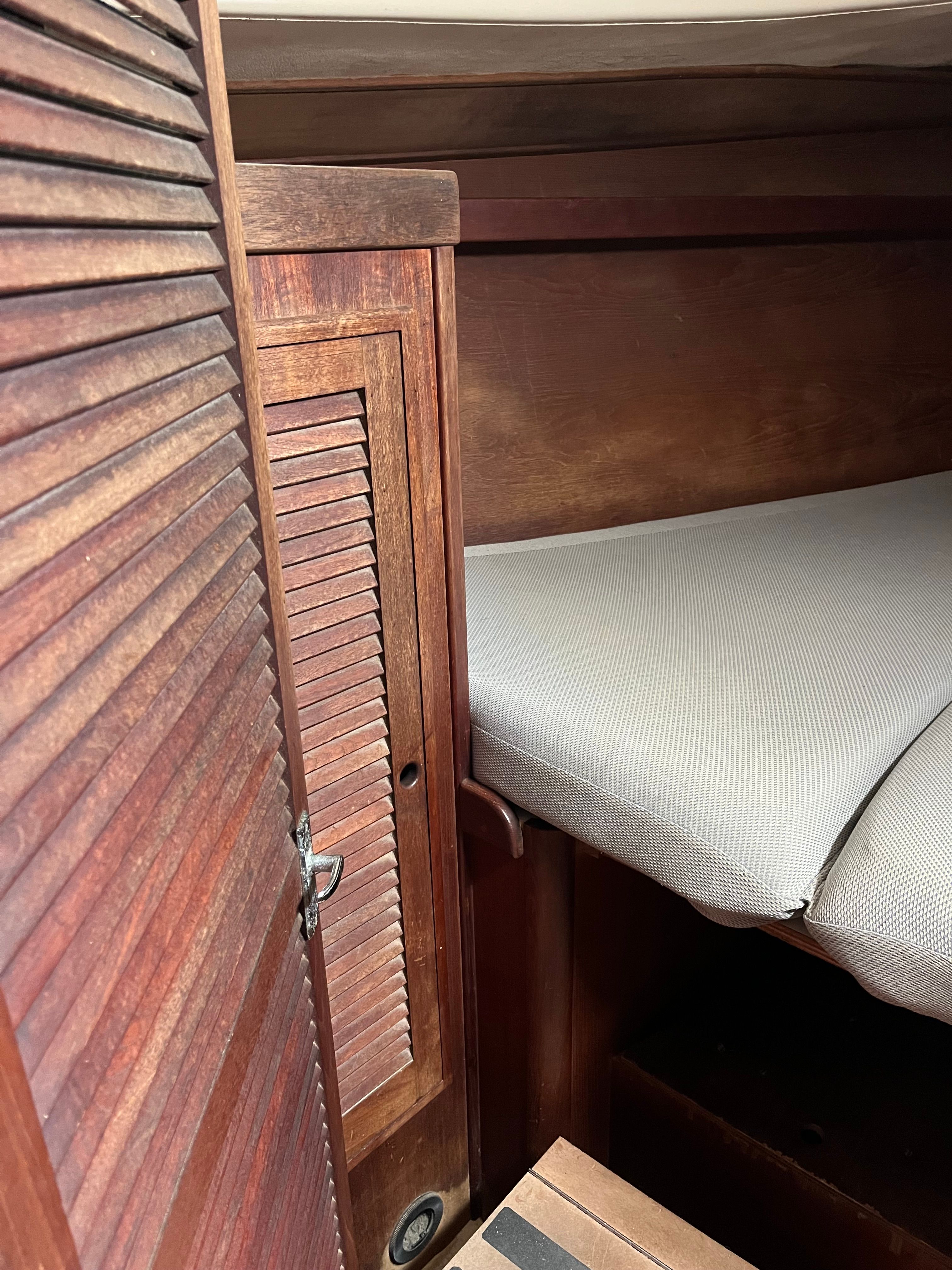 Interior of a 1981 Tartan Sloop with wooden cabinetry and cushioned bed.
