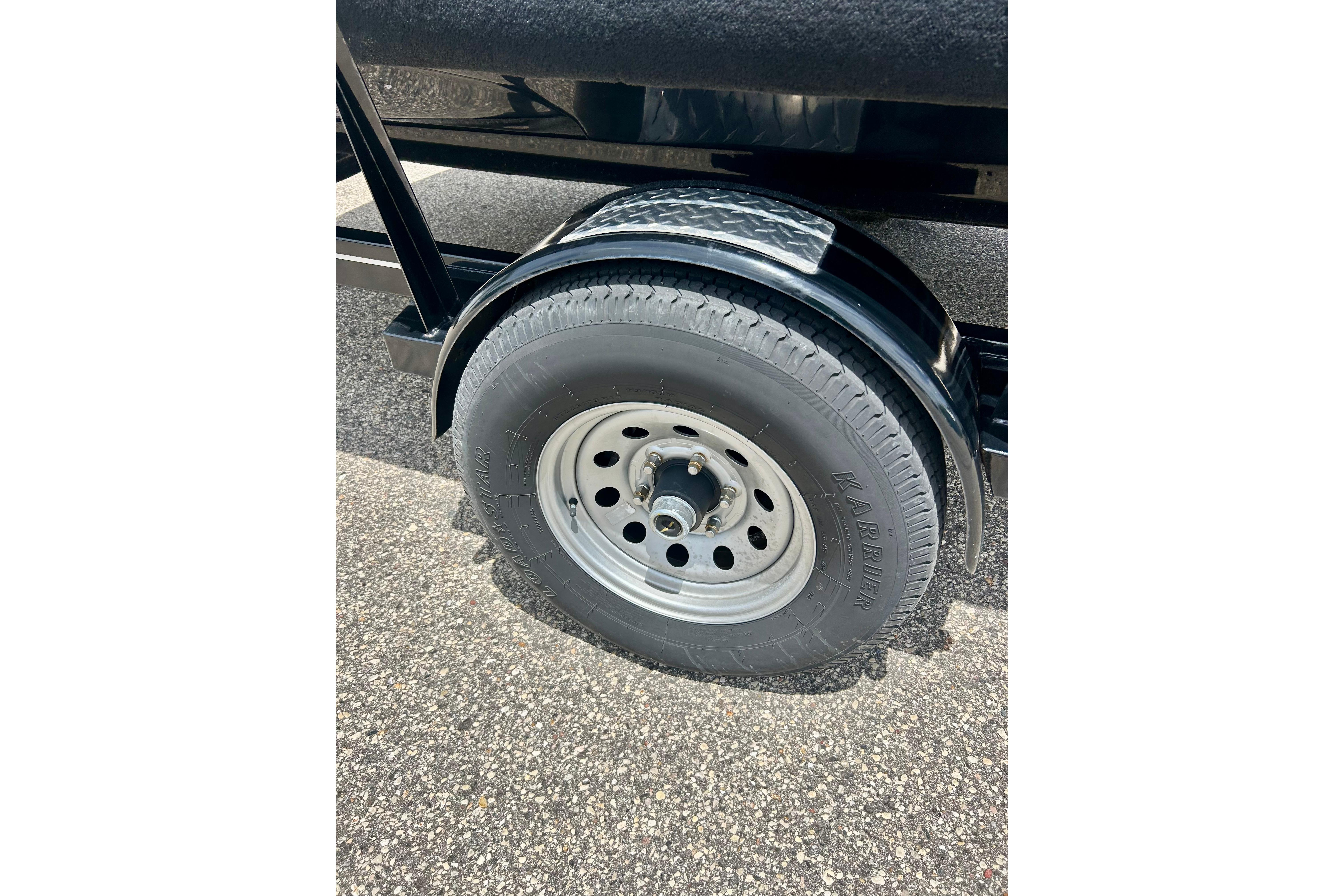 Trailer wheel of a 2021 Scarab 195 ID on asphalt surface.