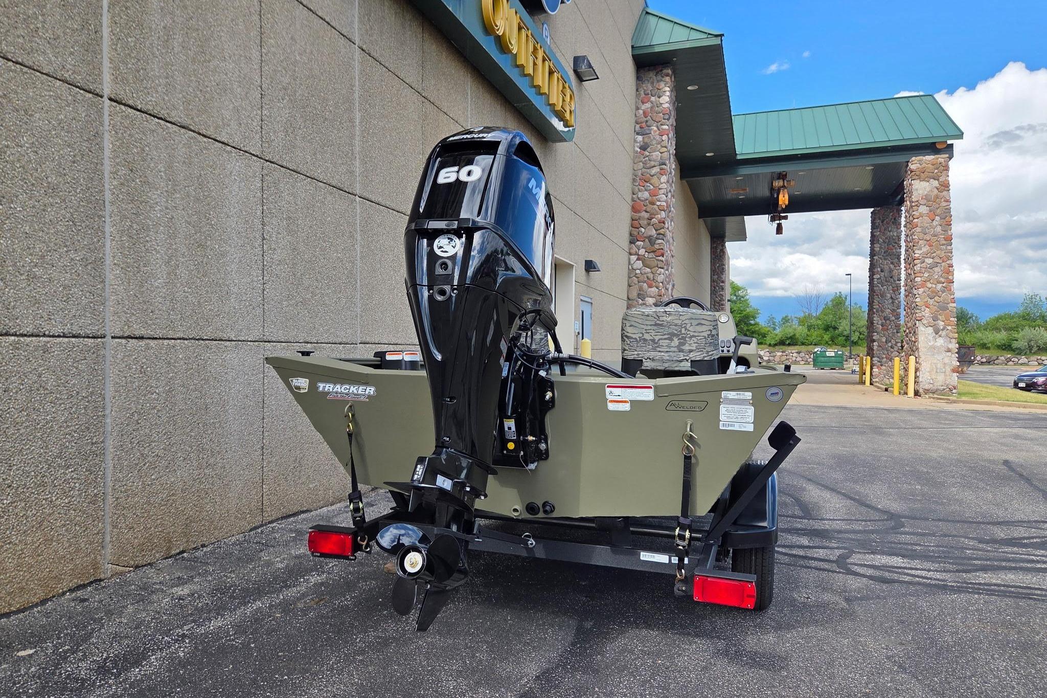 2026 Tracker Grizzly 1754 SC boat with 60 HP motor parked outside a building.