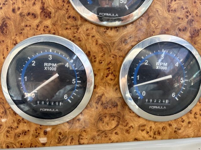 Close-up of two RPM gauges on a boat, mounted on a wood-like surface.