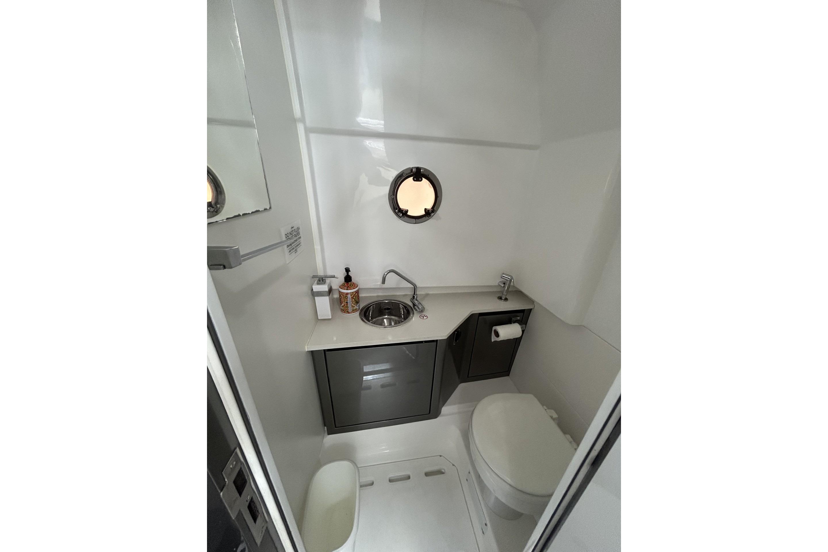 Modern bathroom interior of 2023 Schaefer V33 yacht with sink, toilet, and porthole window.
