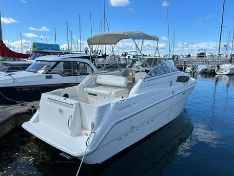 A 1997 Bayliner 2566 Ciera is docked in the water, surrounded by other boats.