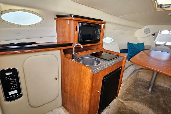 2004 Rinker Fiesta Vee 250 cabin interior with kitchenette and seating area.