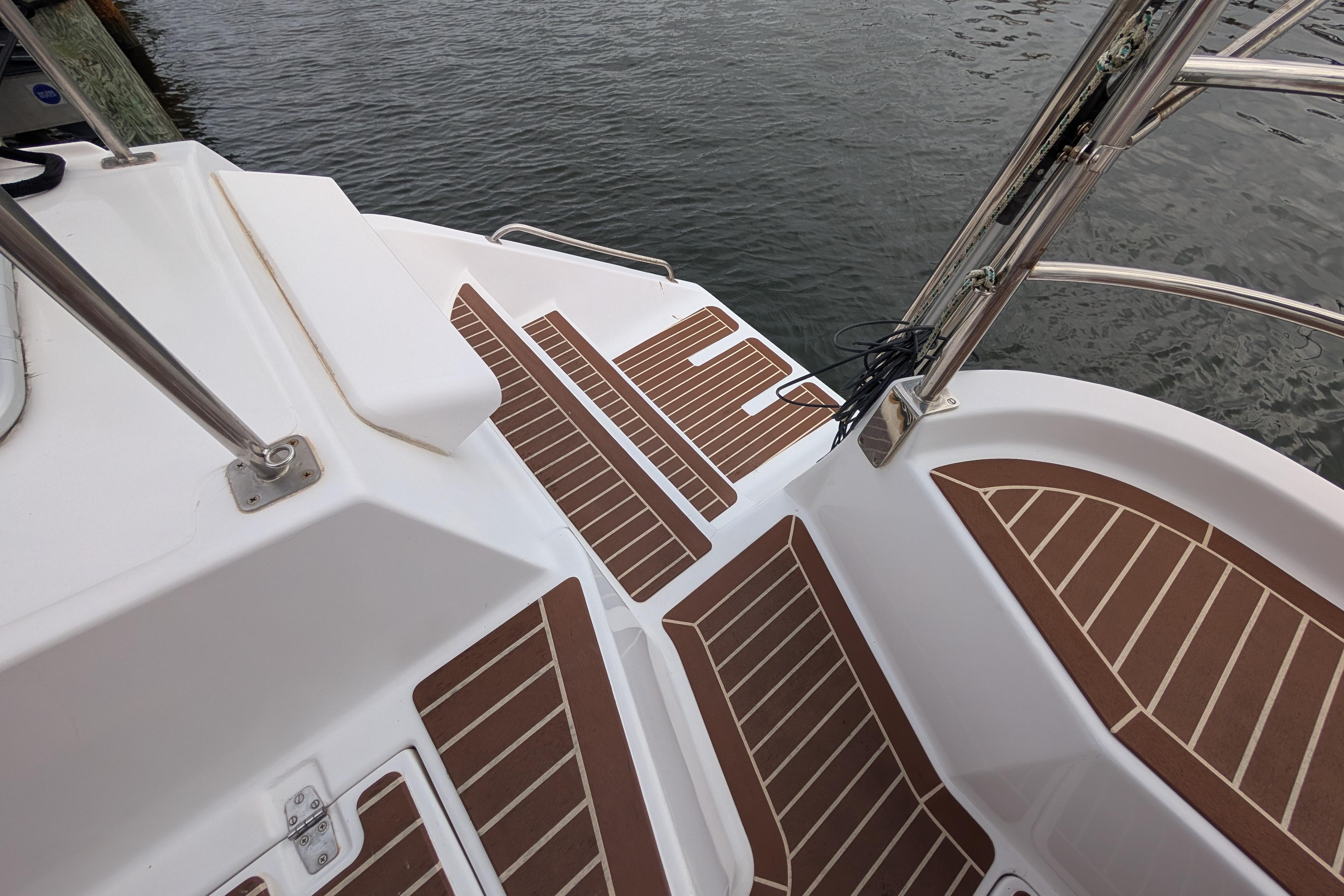 Deck of 1999 Island Spirit 37 sailboat with teak-style flooring by the water.