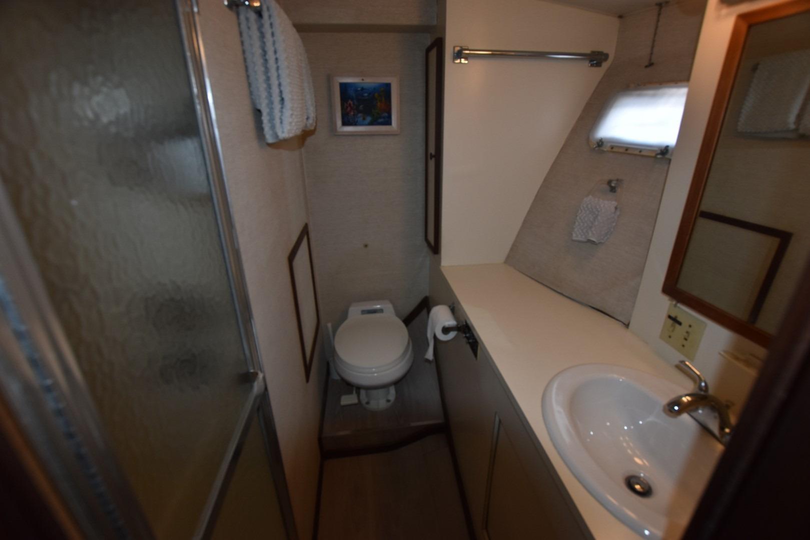 Bathroom interior of 1983 Hatteras 50 Convertible yacht, featuring sink, toilet, and shower.