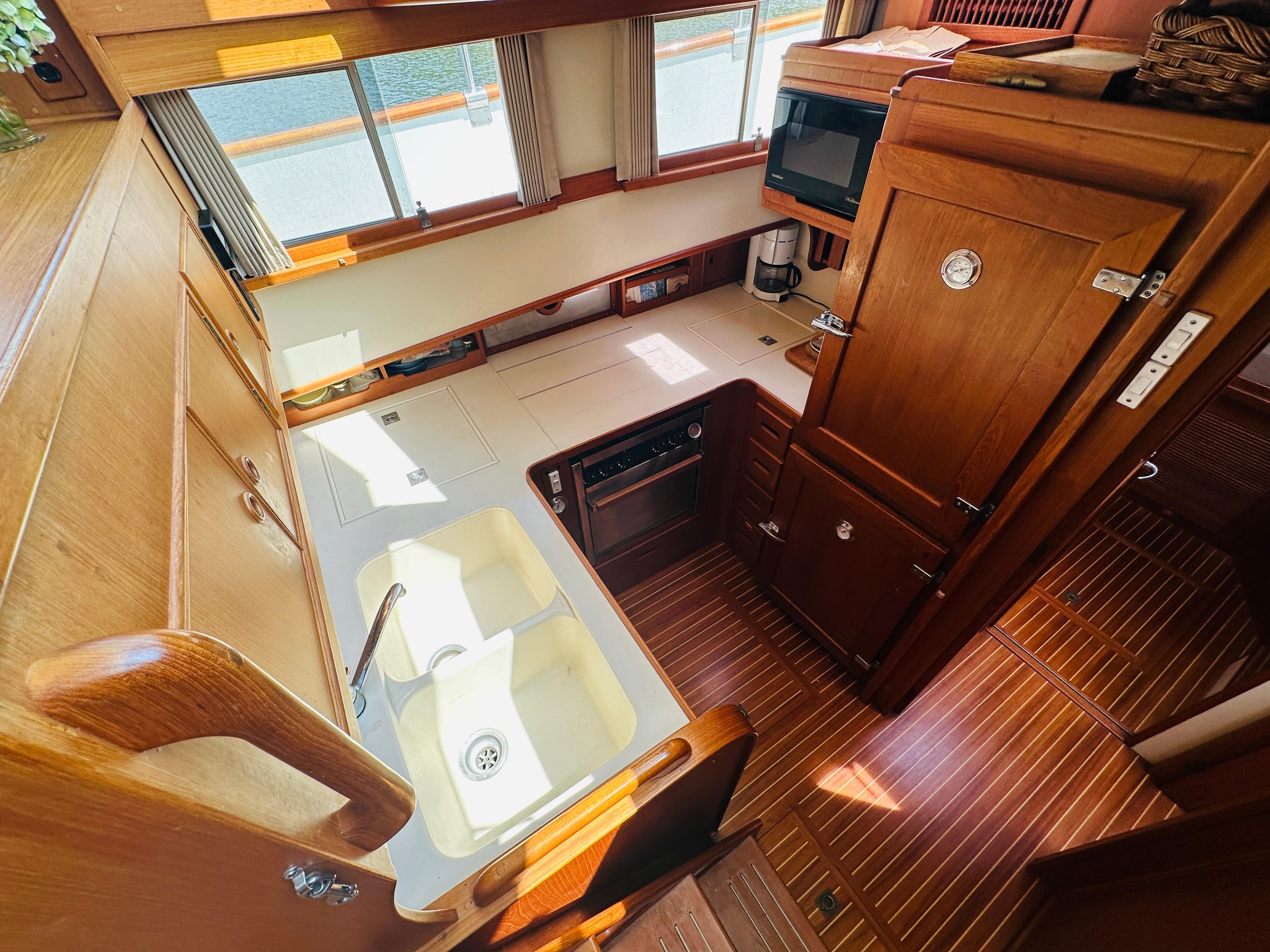 1998 Grand Banks 49 Classic yacht kitchen with wooden cabinetry and dual sink.
