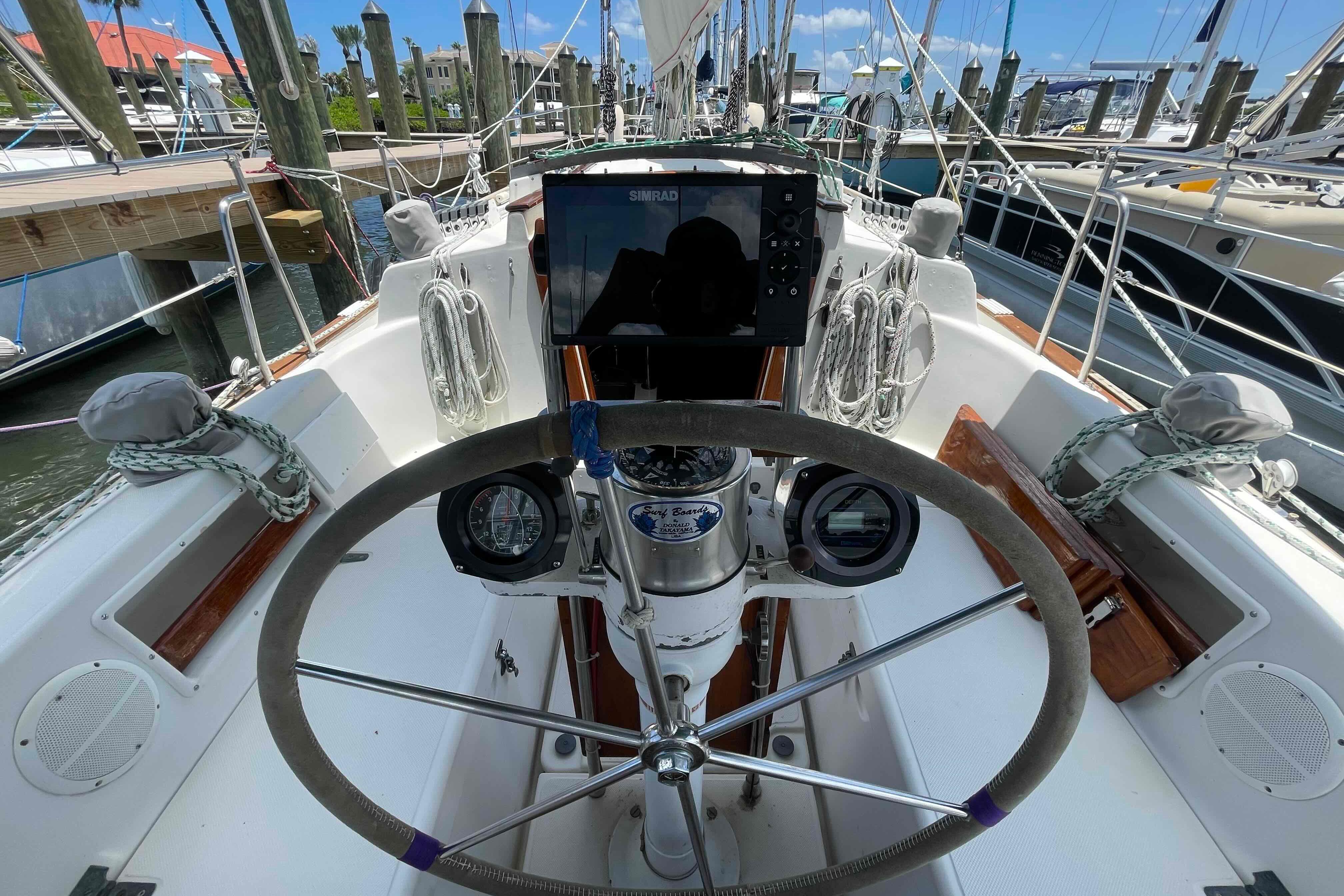Cockpit view of a 1987 Pacific Seacraft 34 sailboat, featuring steering wheel and navigation instruments.