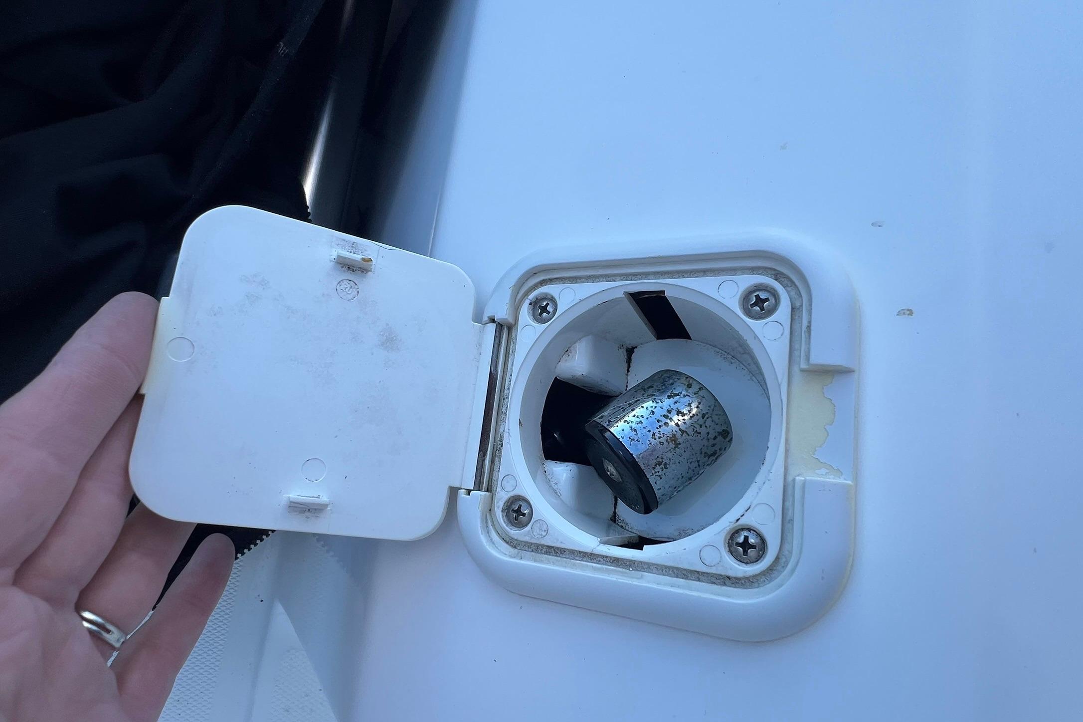 Boat fuel cap on a 2006 Edgewater 245CC, partially open with visible metal component.