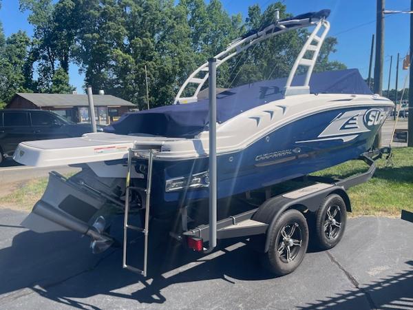 2023 Chaparral 21 Surf boat on trailer, blue and white design, parked outdoors.