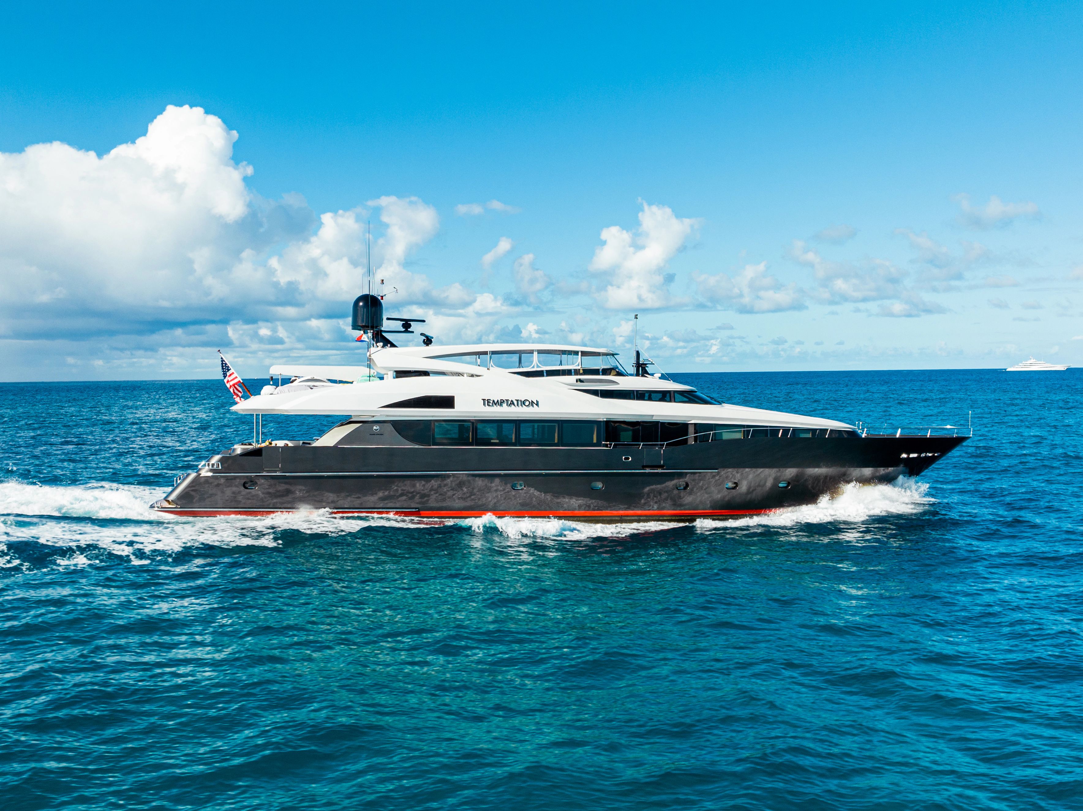 A luxury yacht cruising on the open sea under a blue sky.