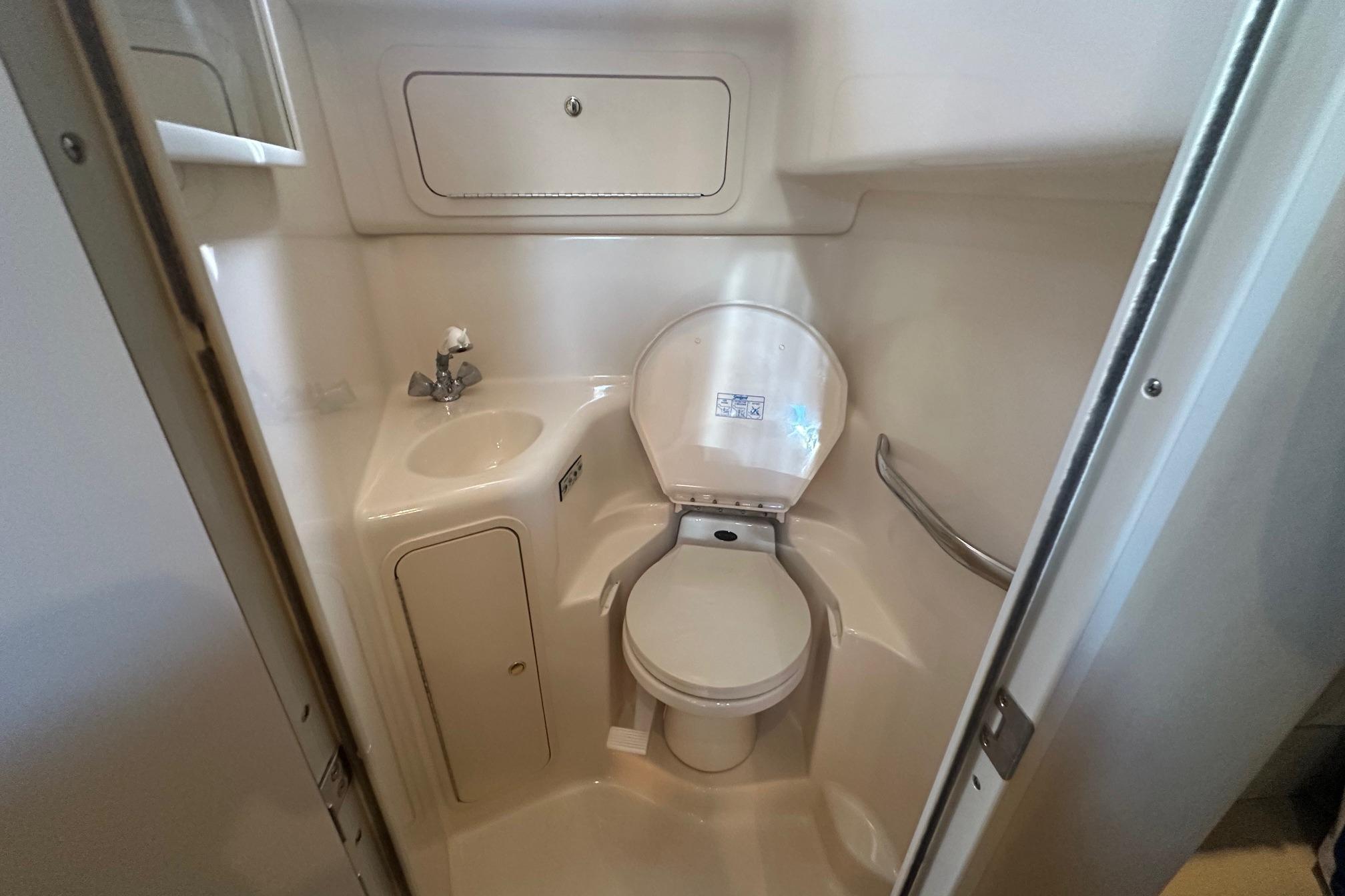 Compact bathroom in 2001 Sea Ray 410 Sundancer yacht, featuring toilet and sink.