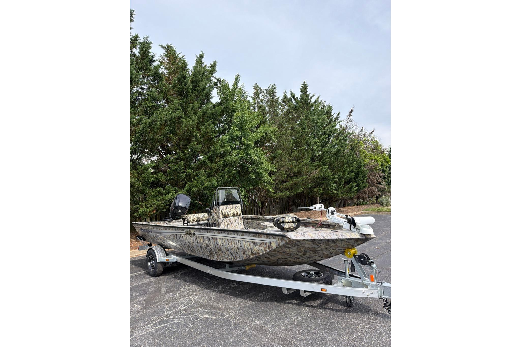 2026 Ranger RB190 boat with camouflage design on a trailer, parked near trees.